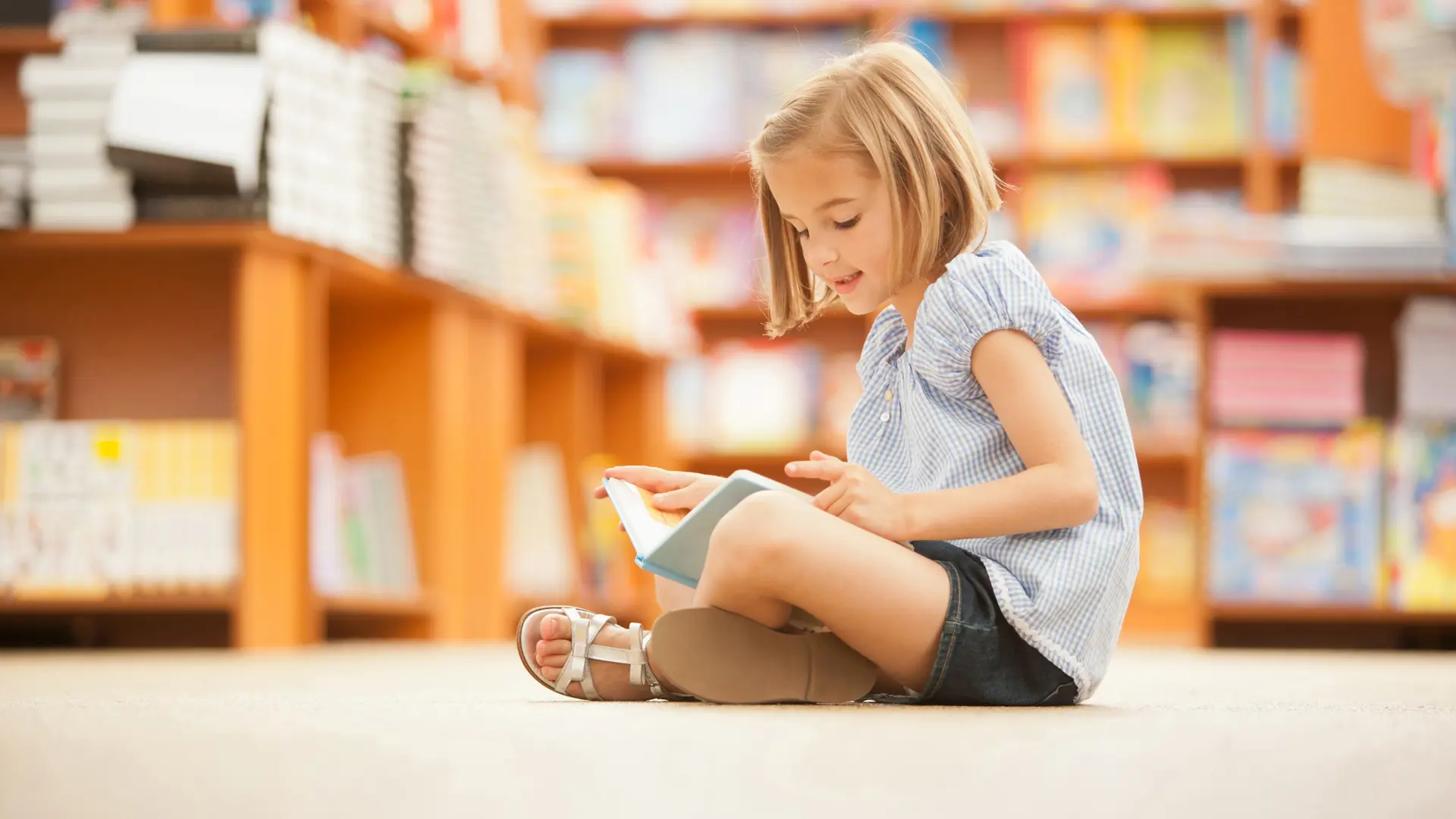 Flicka läser bok i bibliotek