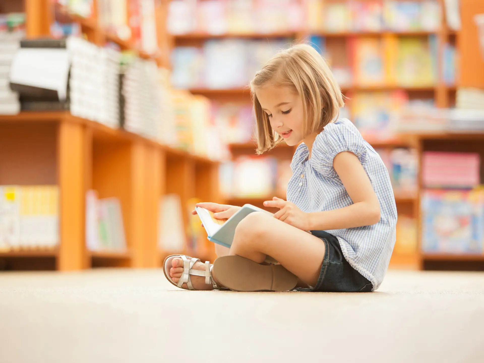 Flicka läser bok i bibliotek