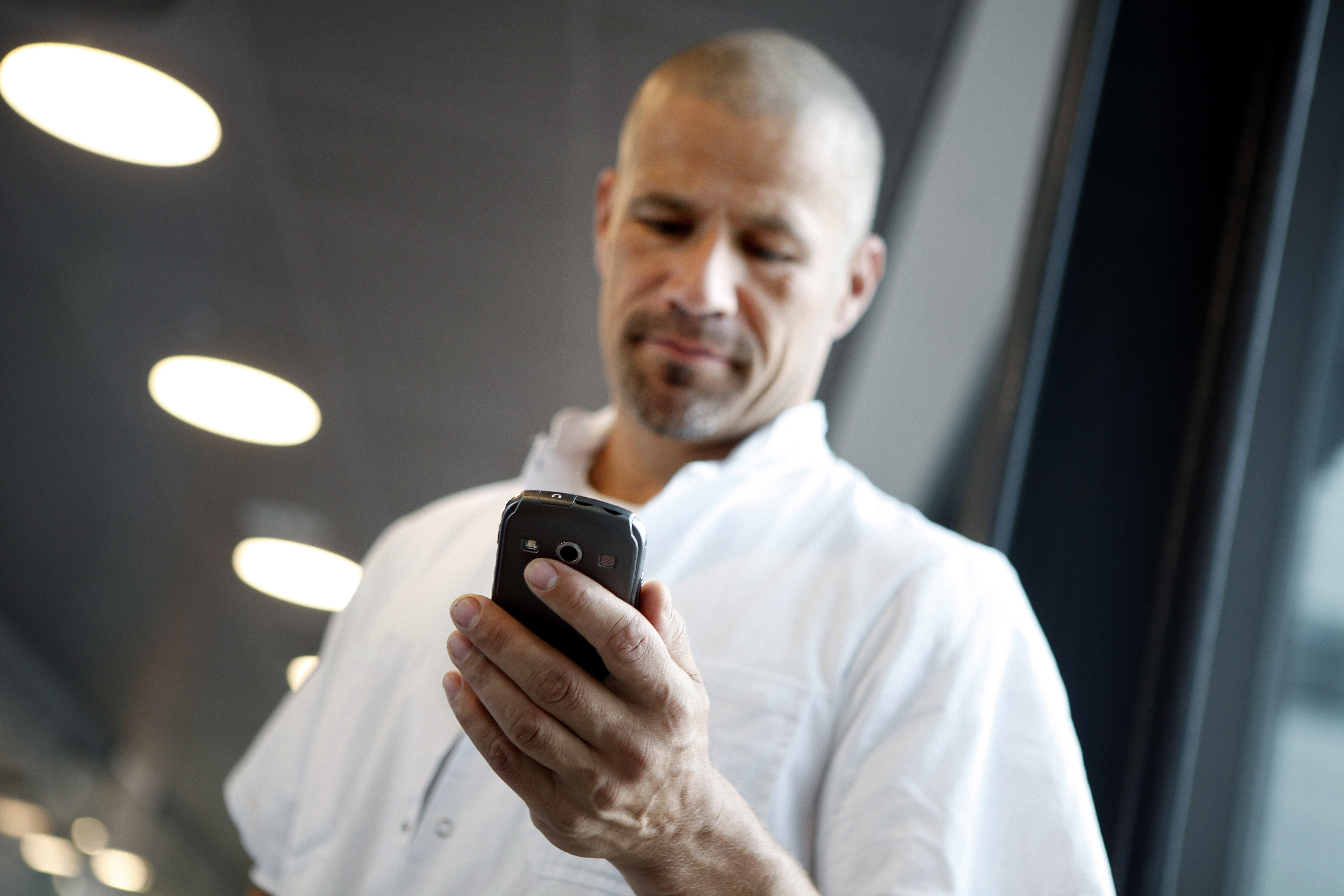 Mandlig læge kigger på smartphone med Columna Flow Task Management