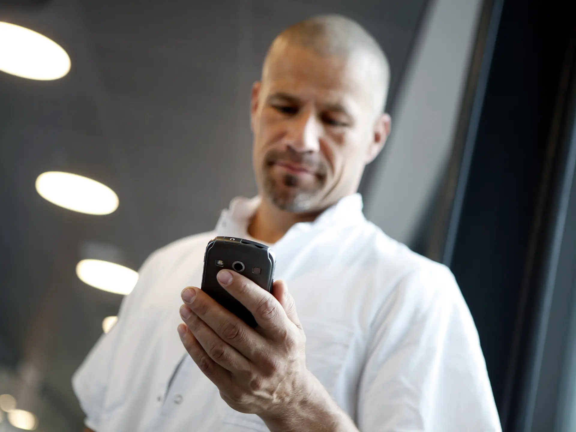 Male doctor looking at smartphone with Columna Flow Task Management