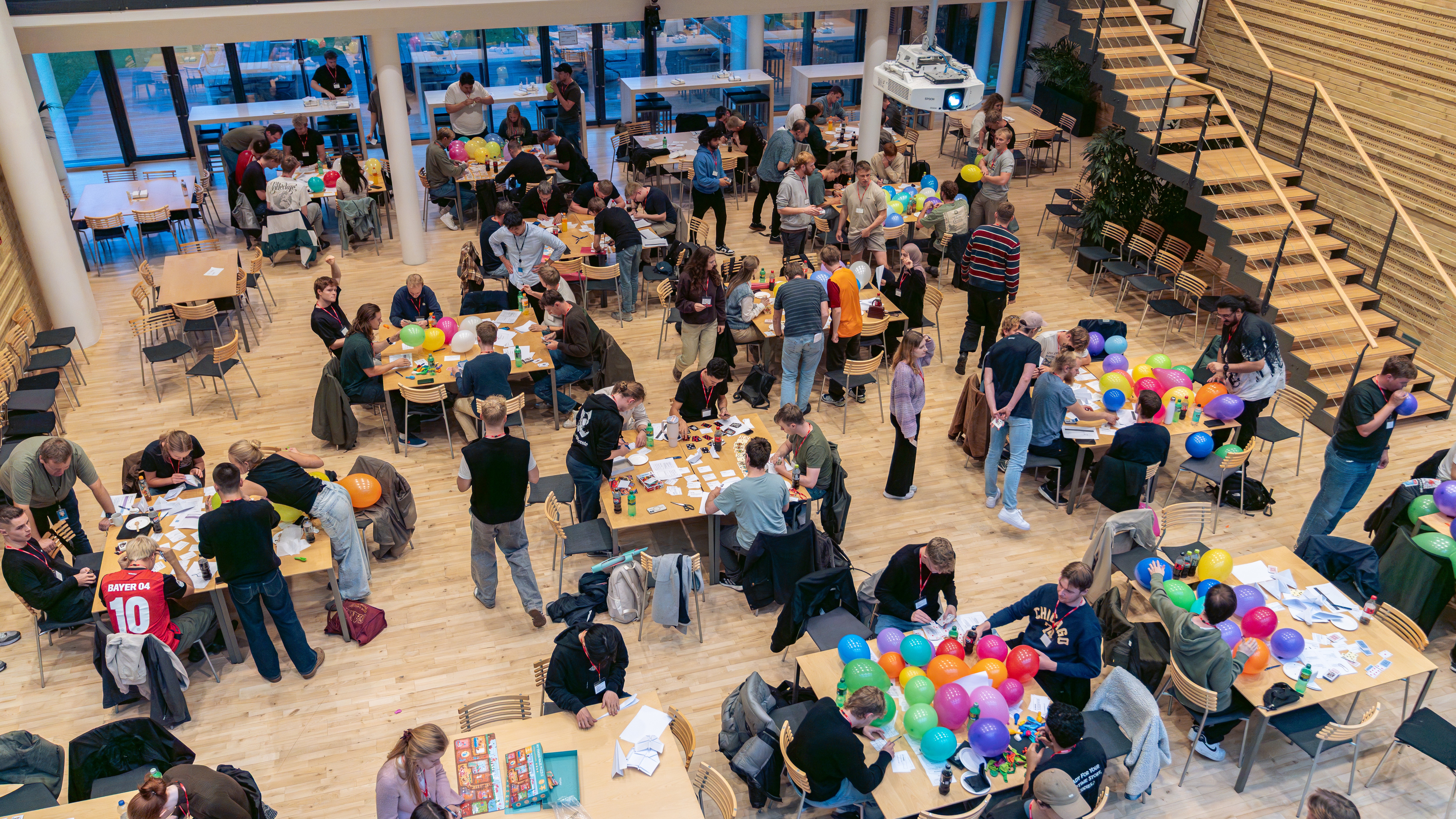 Students participating in Scrum Game course with colorful balloons in modern cafeteria