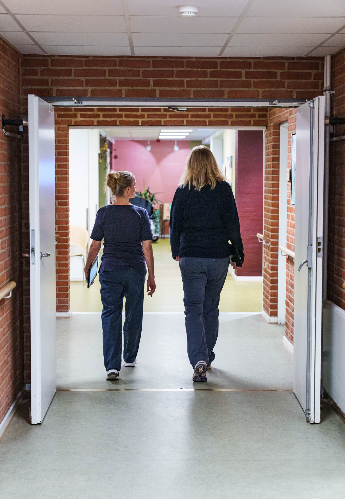 Two nurses walking together along a hospital corridor.