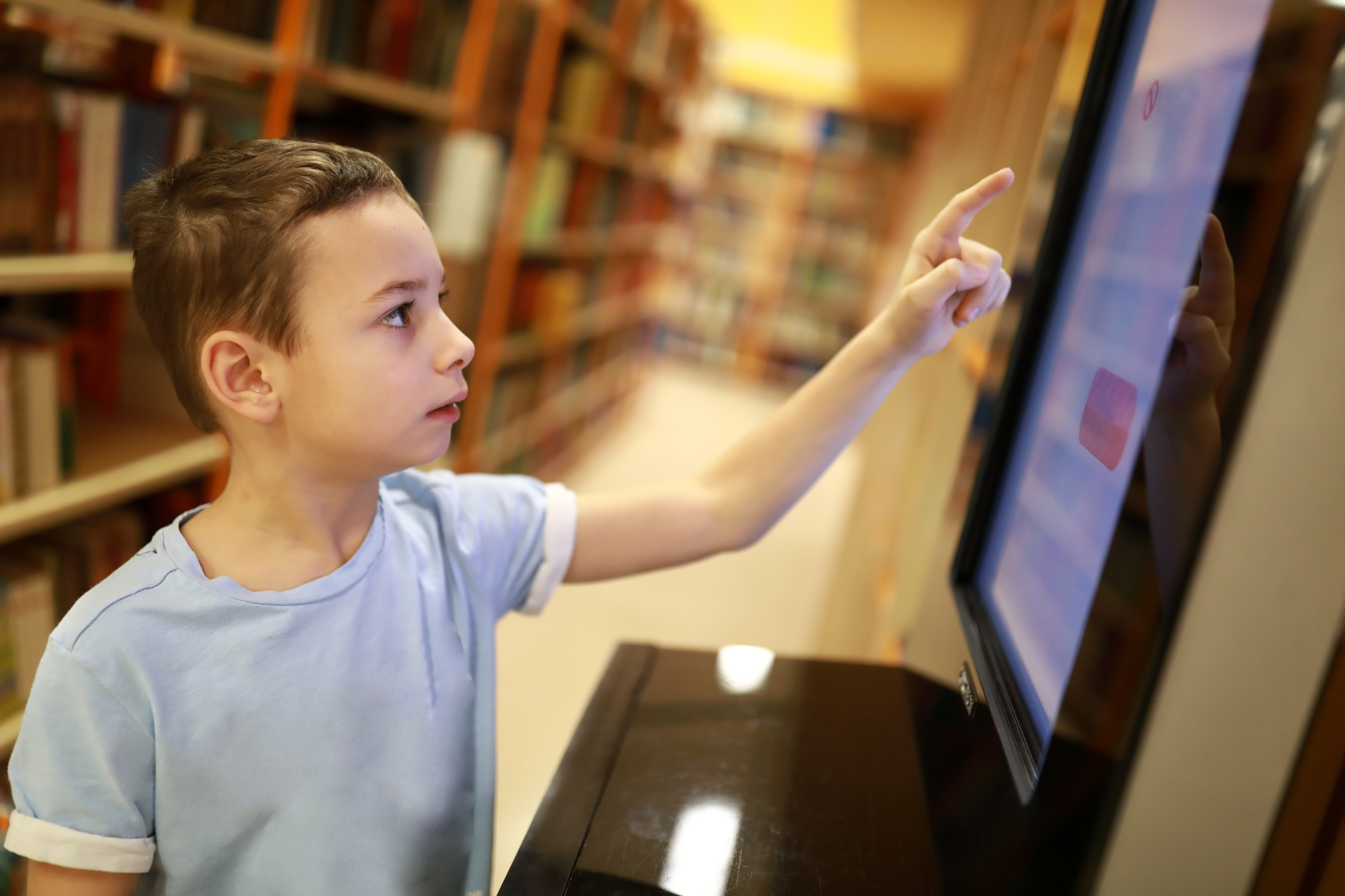Young boy uses computer in library for selfservice