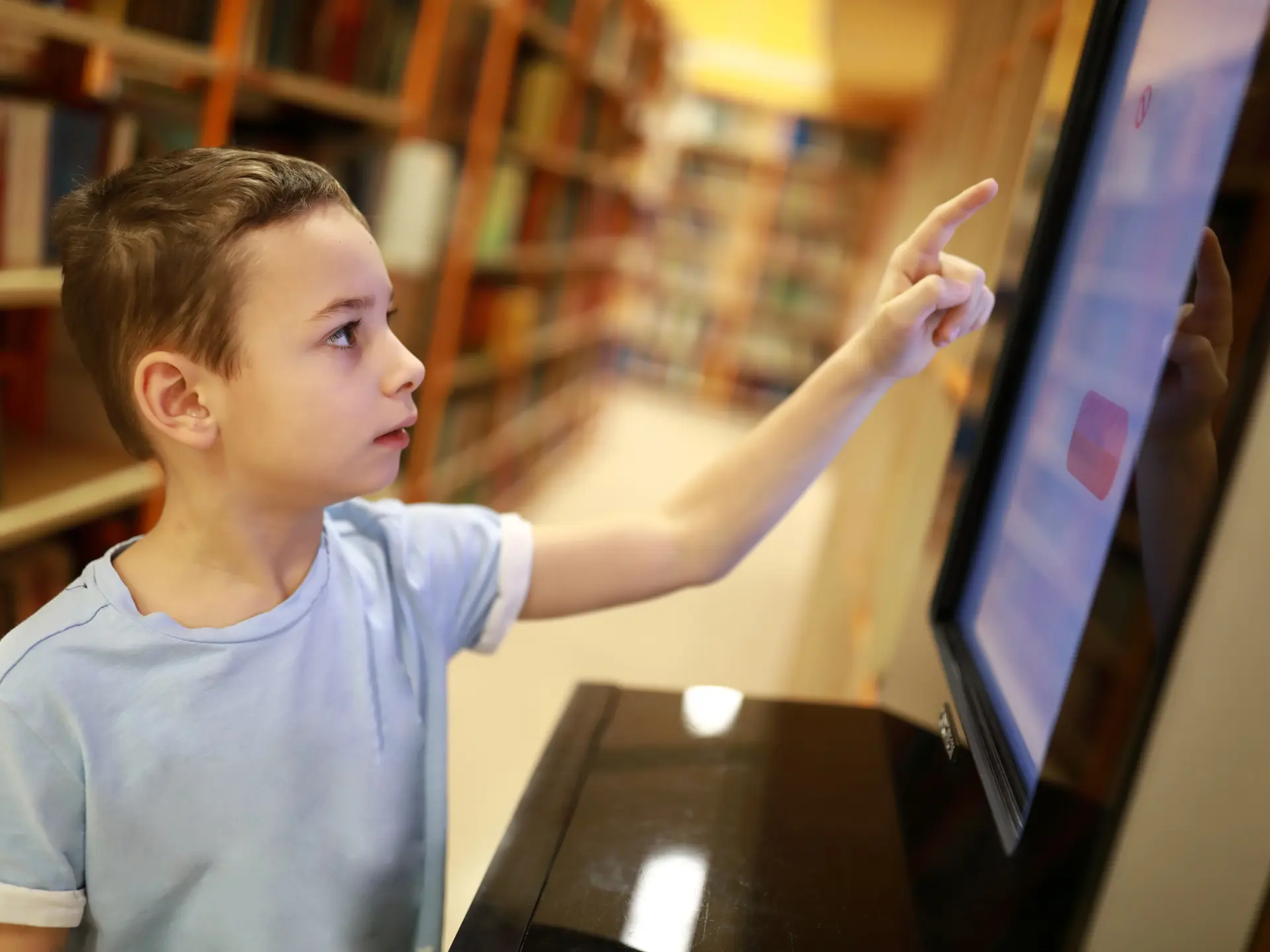 Young boy uses computer in library for selfservice