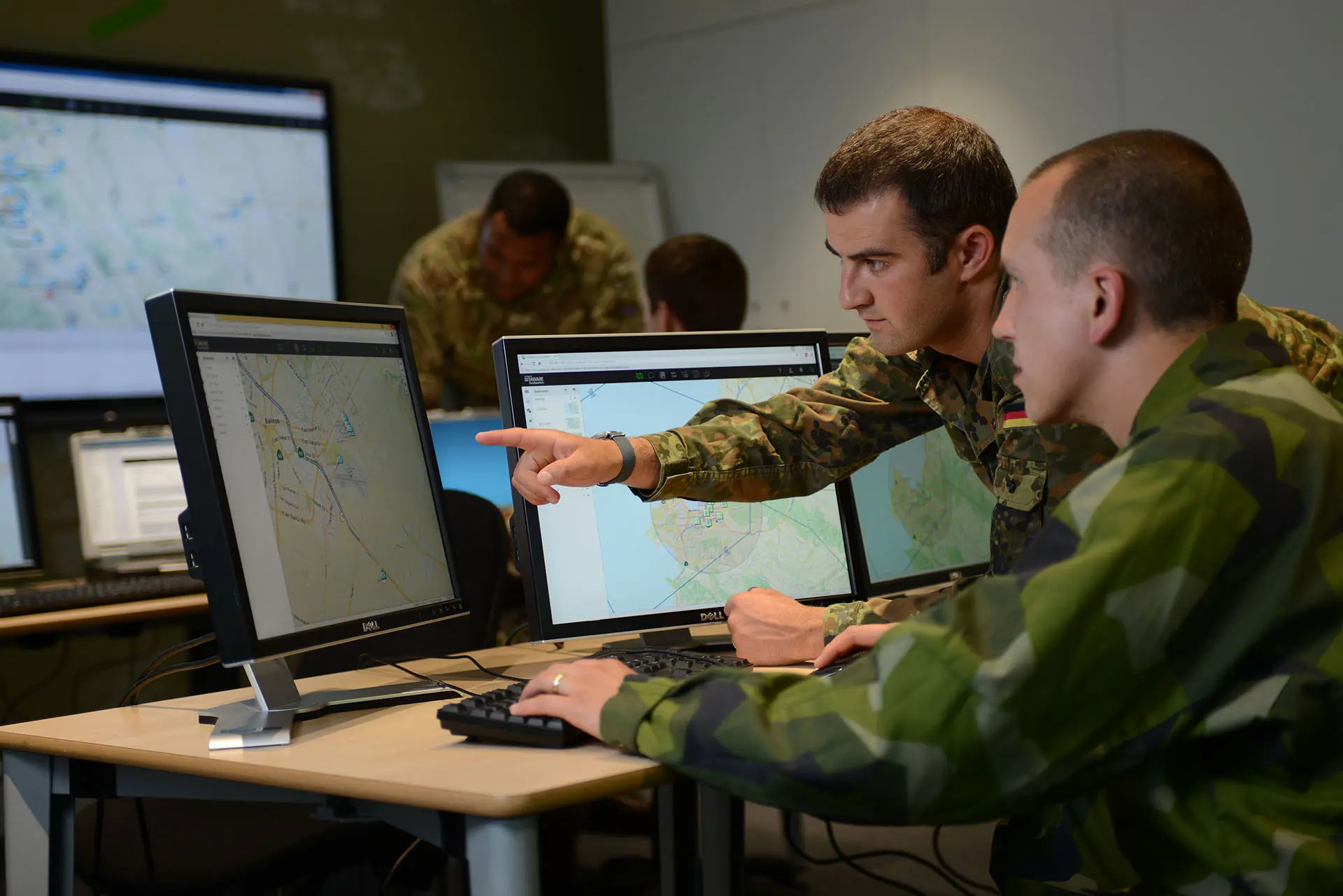 Military staff discussing a matter while looking at SitaWare on their screens