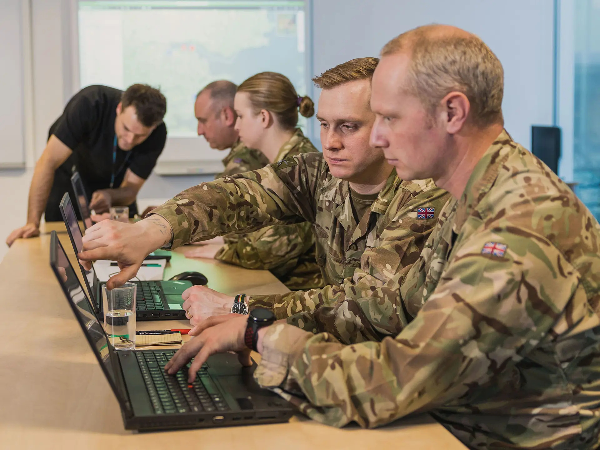 Four soldiers sitting at desks and training in C4ISR