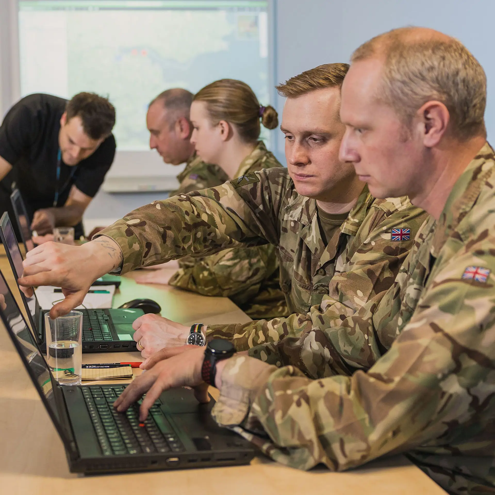 Four soldiers sitting at desks and training in C4ISR