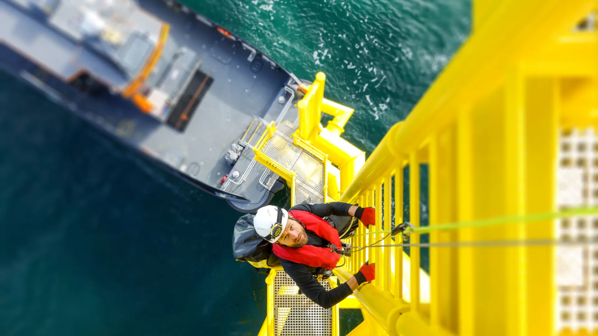 An operator climbing the ladder of an offshore wind turbine