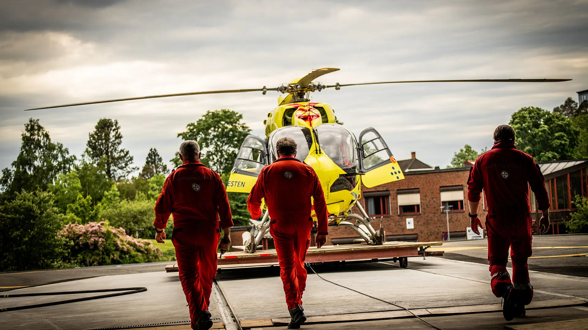 Tre ambulancereddere foran en lægehelikopter 