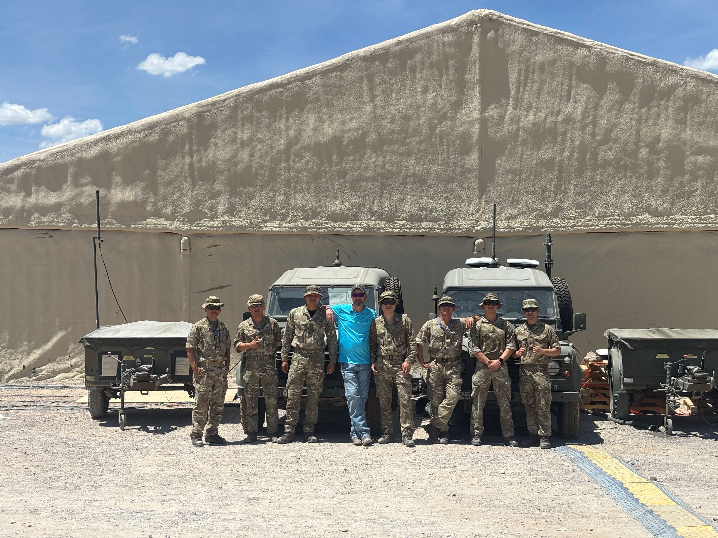 Jeff Fisher stands with a group of soldiers in front of military vehicles at PC-C6.