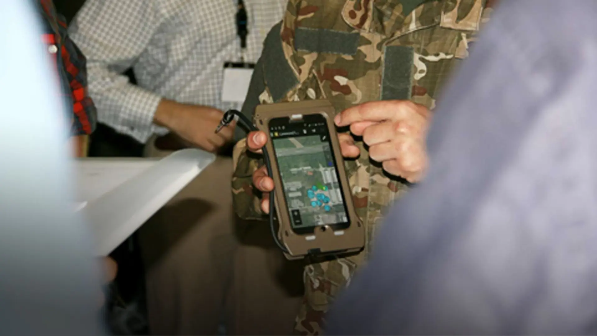 Military person pointing at a phone with SitaWare software