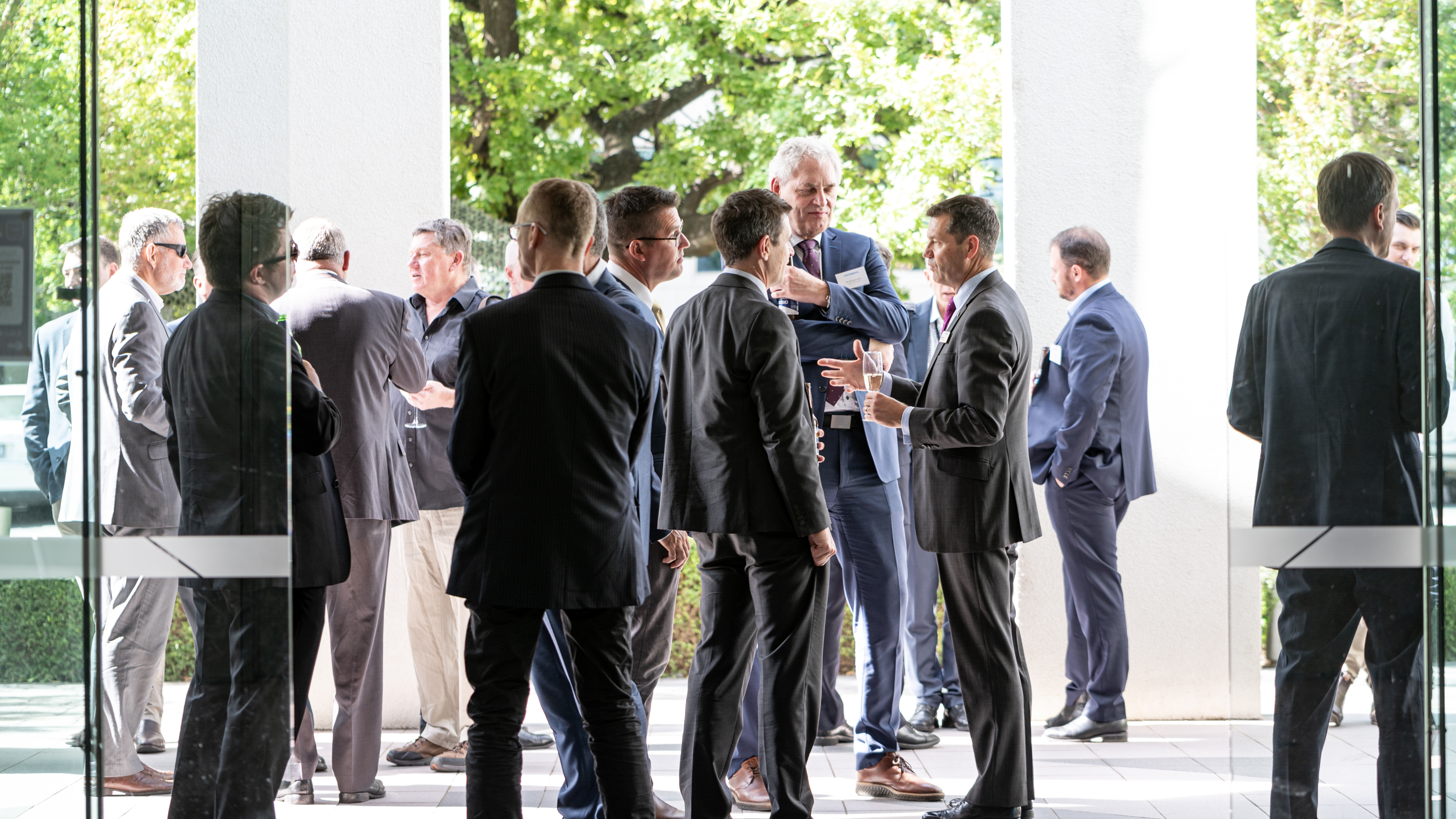 Guests network and converse outside Systematic’s newly opened Asia Pacific headquarters in Canberra, Australia, including employees, partners, and customers in professional attire.