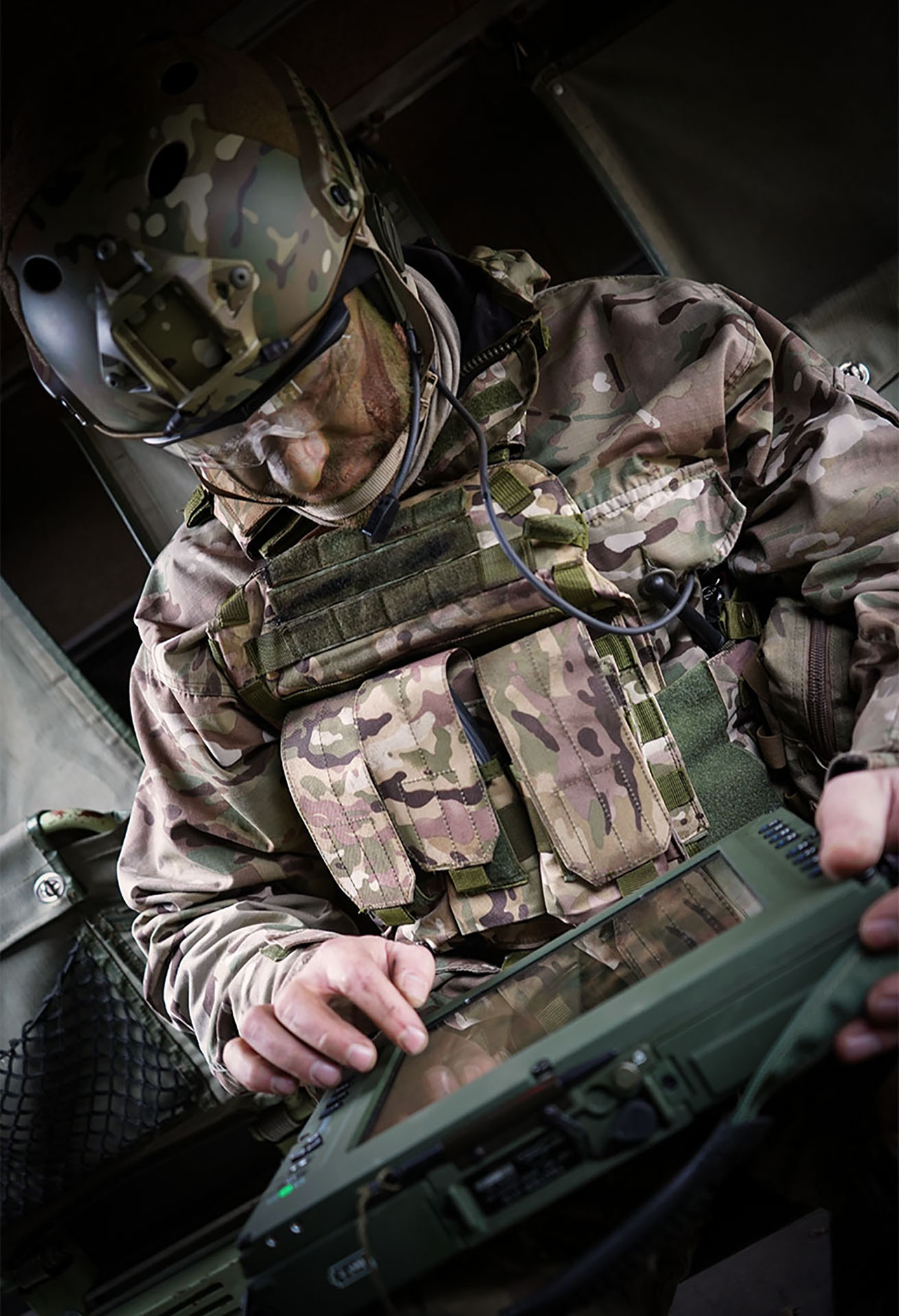 Soldier in camouflage uniform operating a rugged tablet with SitaWare Frontline software inside a military vehicle.