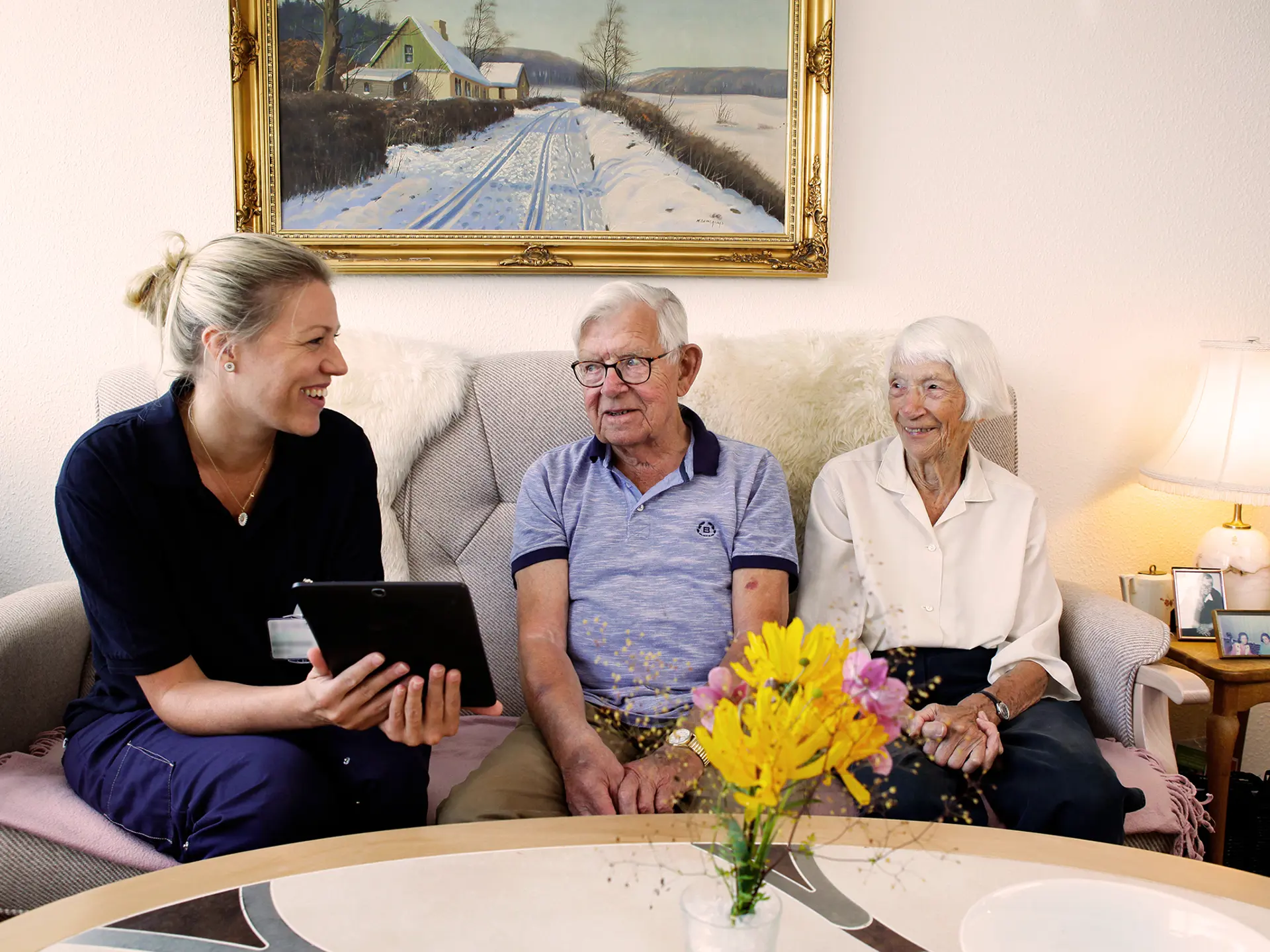 Socialrådgiver taler med to borgere med Columna Cura Omsorg på sin tablet