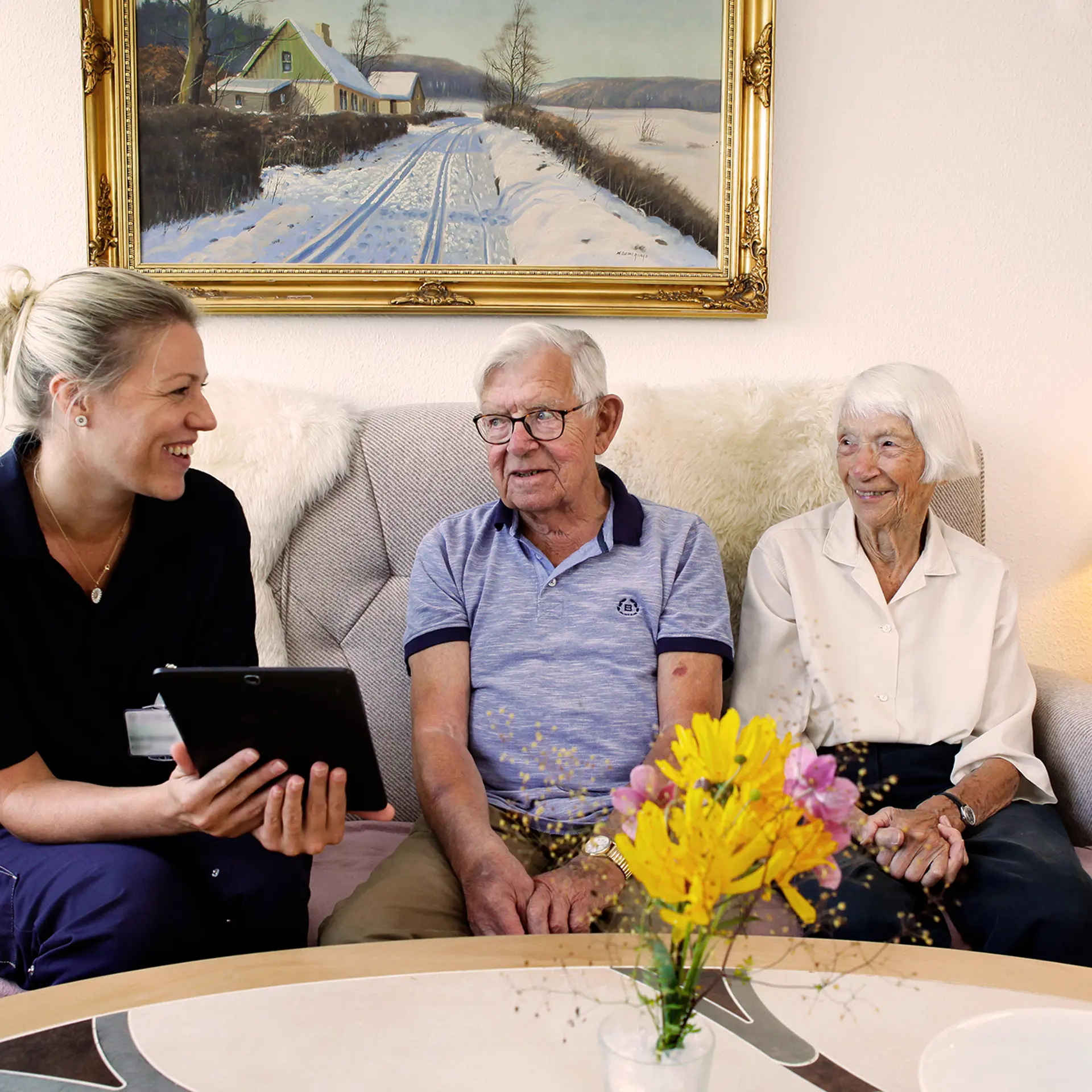 Social worker talking to two citizens using Columna Cura Omsorg on her tablet