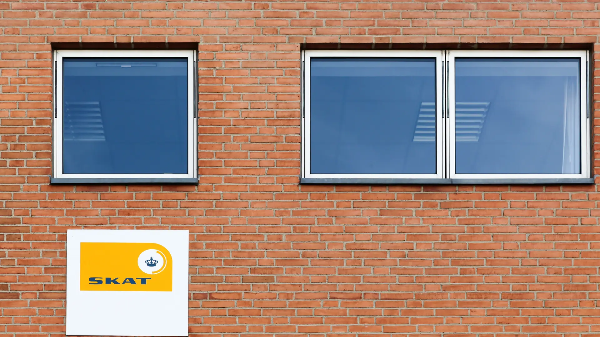 Brick wall with a sign from SKAT (Danish Tax Authority)