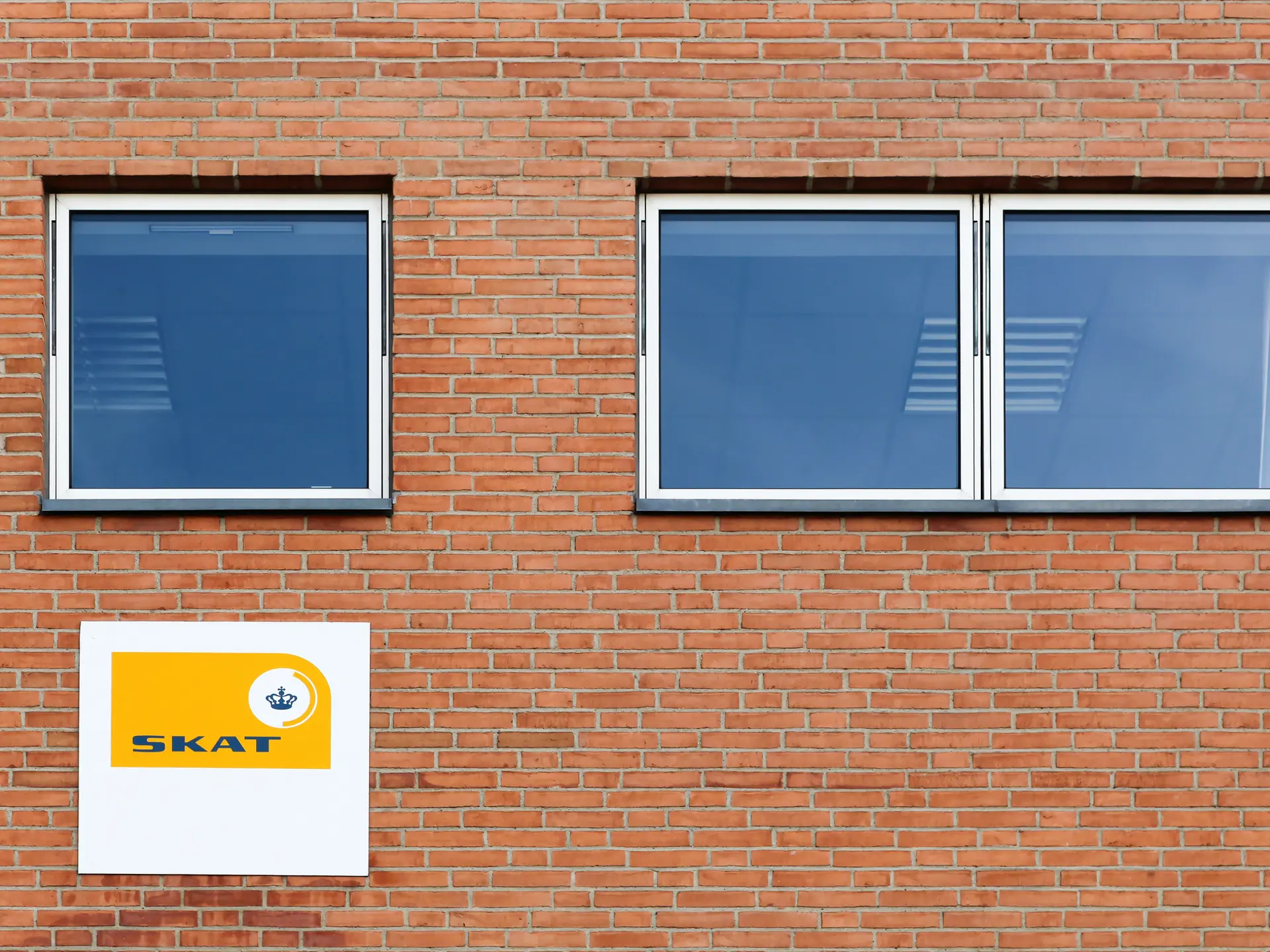 Brick wall with a sign from SKAT (Danish Tax Authority)