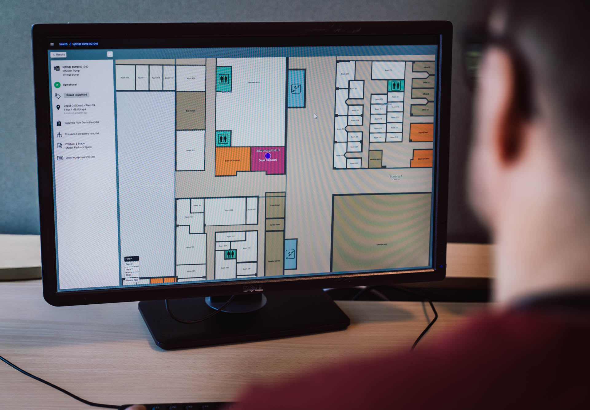Digital facility management floor plan displayed on computer monitor showing building layout with color-coded rooms and equipment tracking