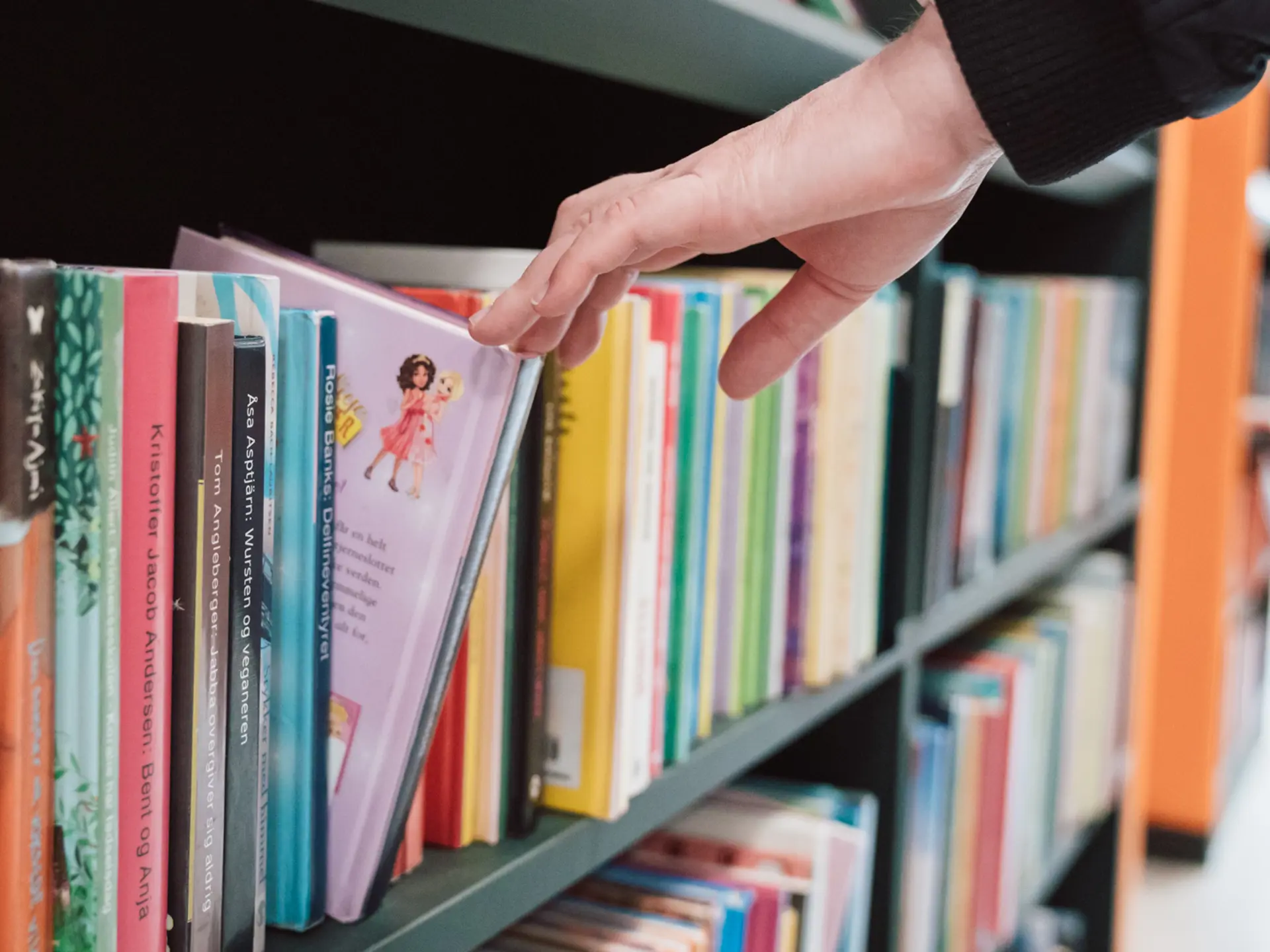 Pige tager en bog ud af en bogreol på et Cicero bibliotek