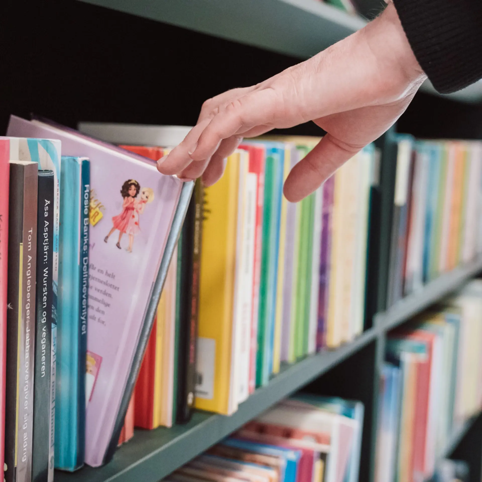 Pige tager en bog ud af en bogreol på et Cicero bibliotek