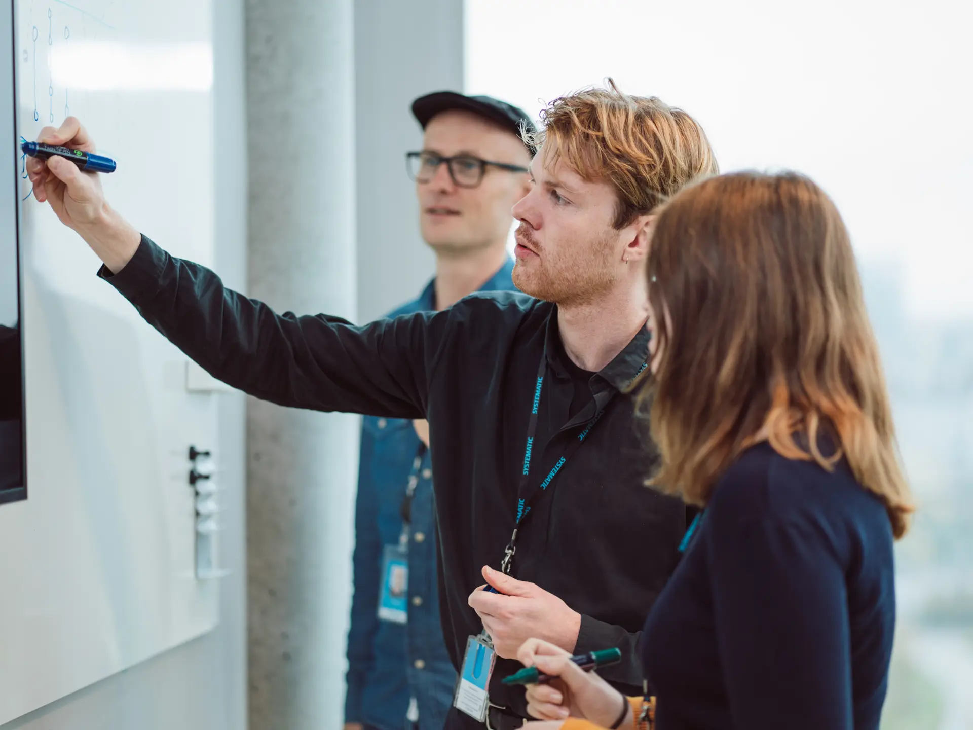 Systematic Employee drawing in white board with colleagues looking