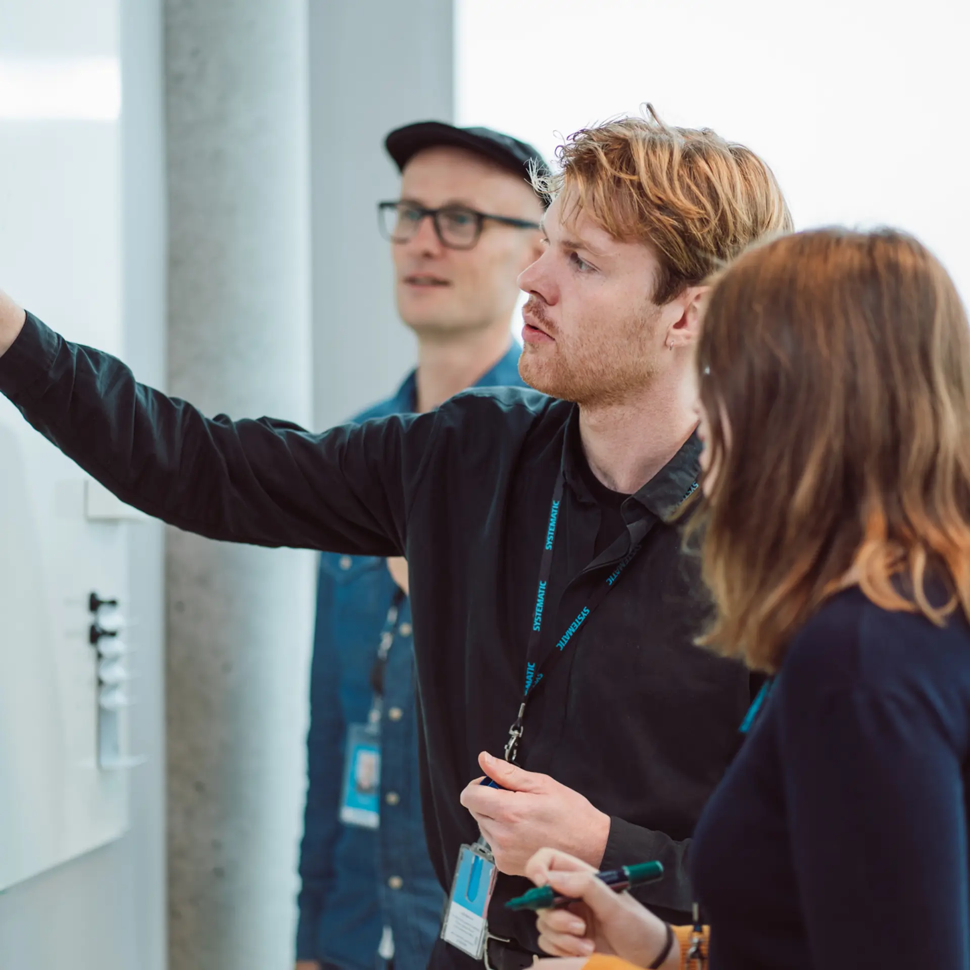 Systematic Employee drawing in white board with colleagues looking
