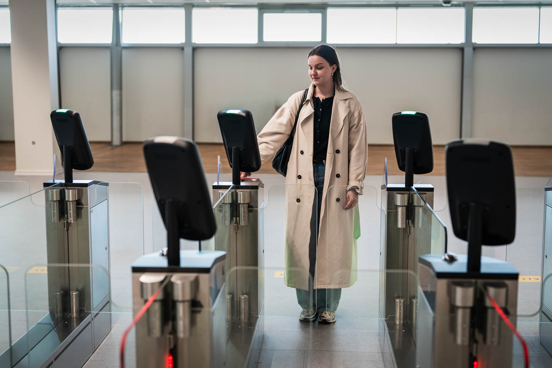 Woman using an automated access control gate and scanning her credentials in a modern security checkpoint.