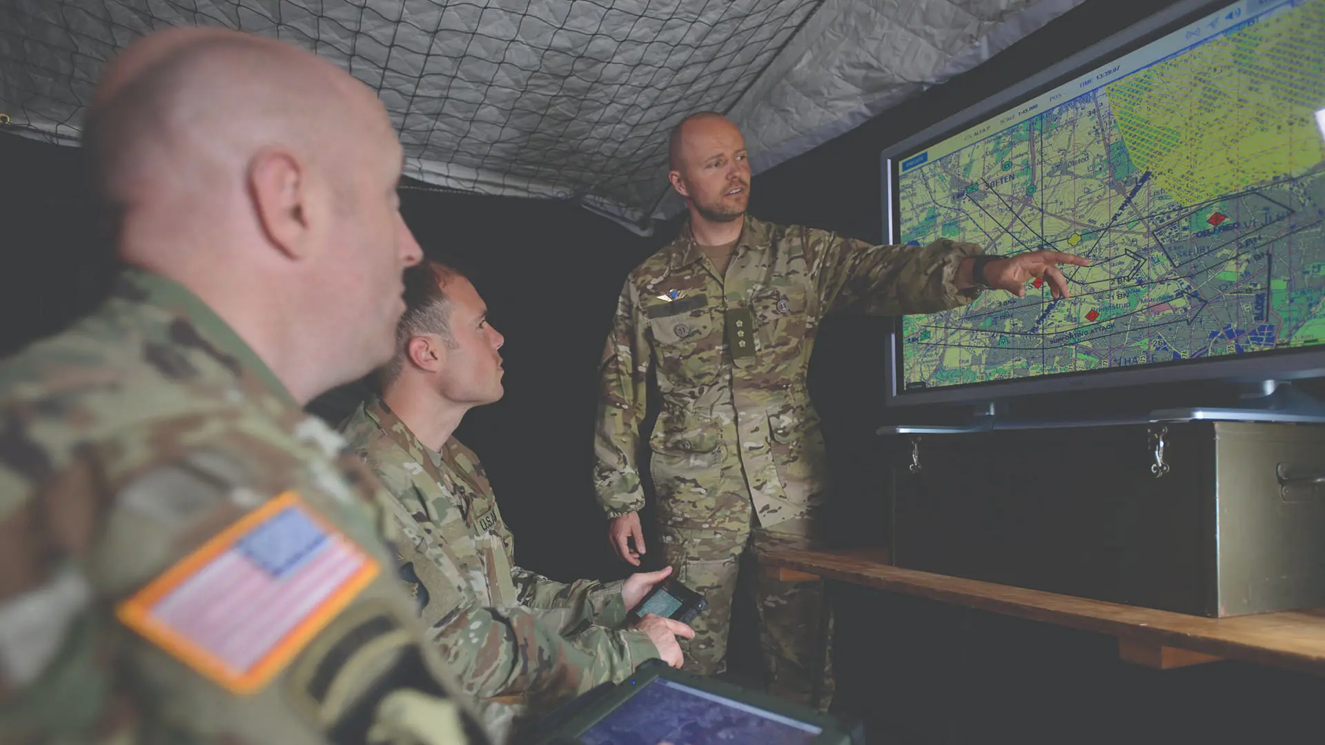 Commander Explaining In Front Of Map On Big Screen