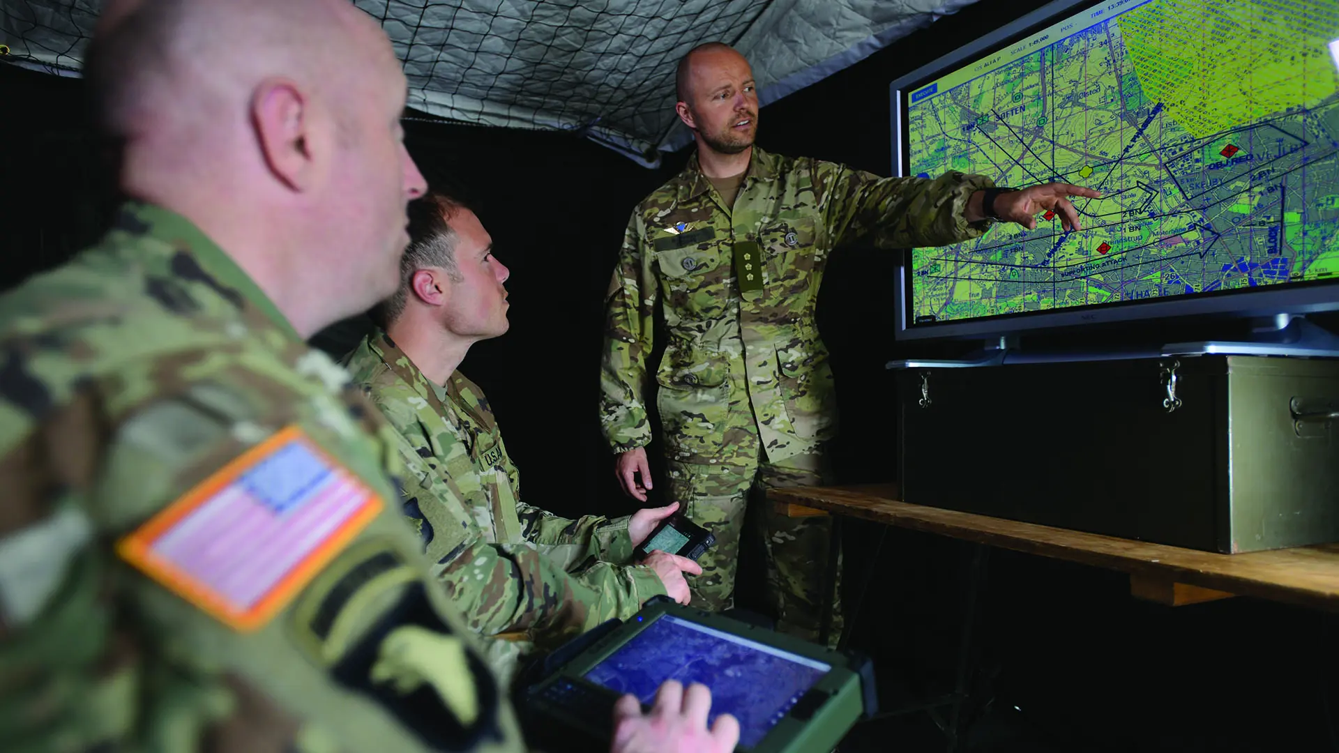 Commander Explaining In Front Of Map On Big Screen