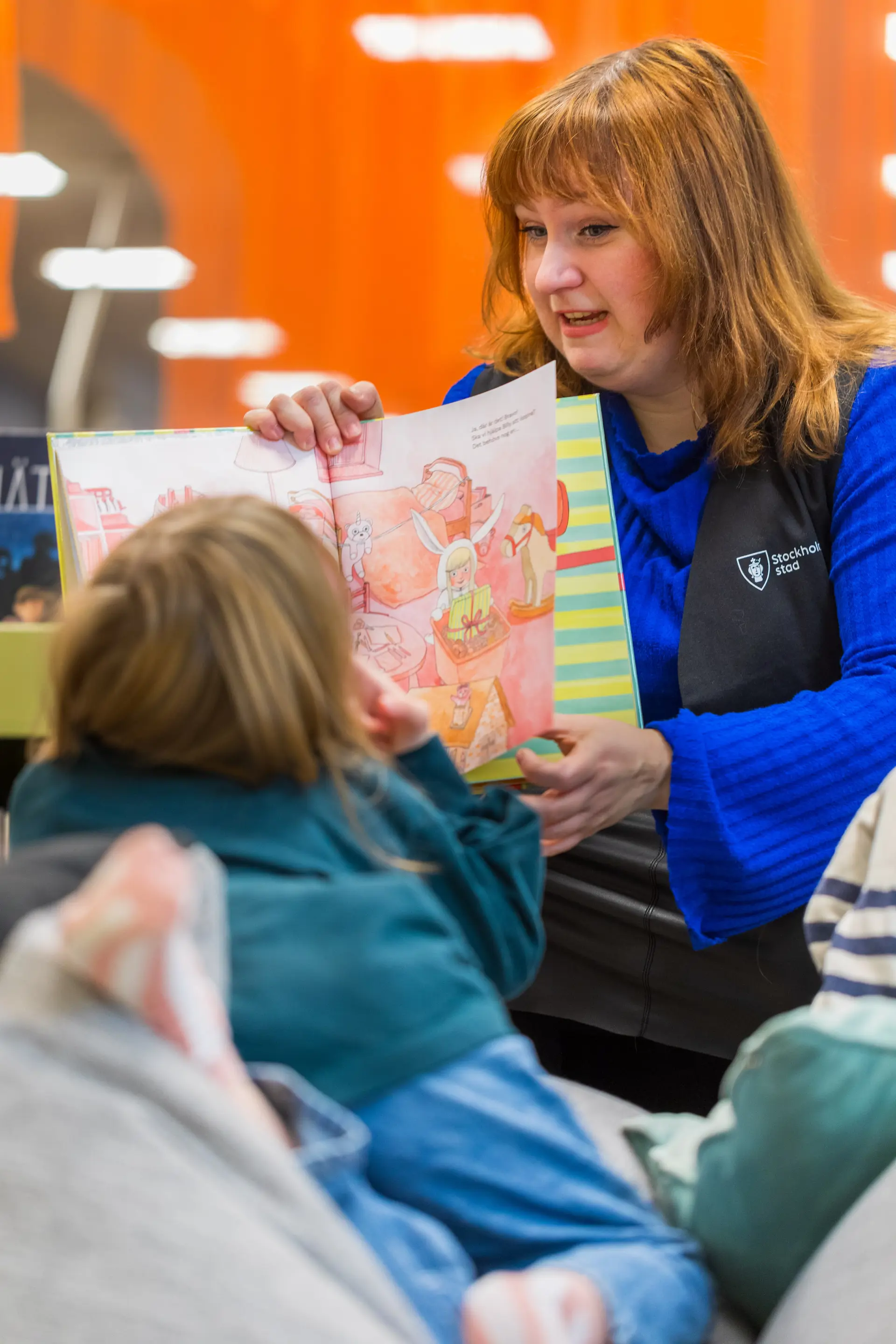 Bibliotekarie läser en bok för barn på Stockholms stadsbibliotek