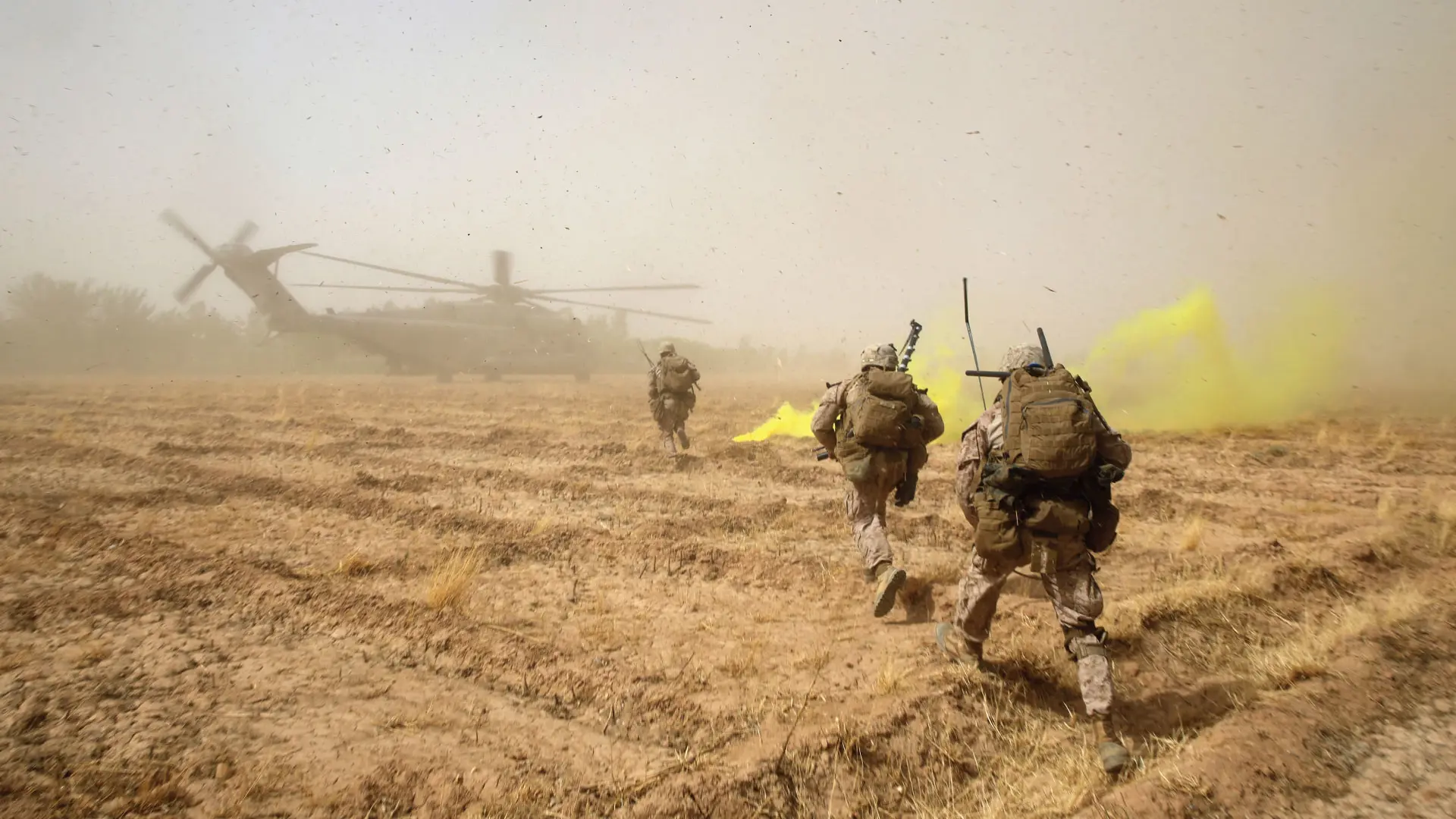 Soldiers run towards a military helicopter