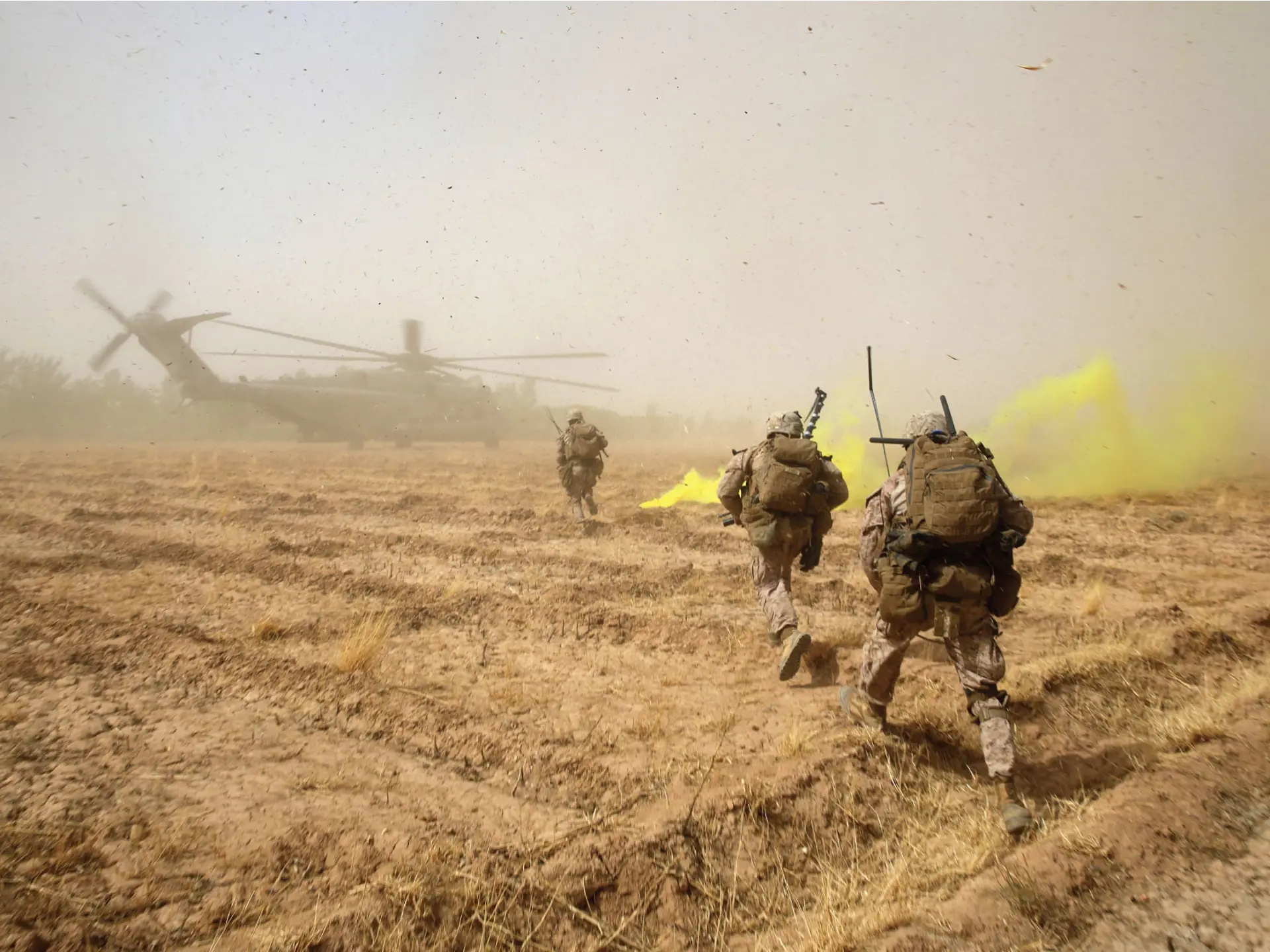 Soldiers run towards a military helicopter