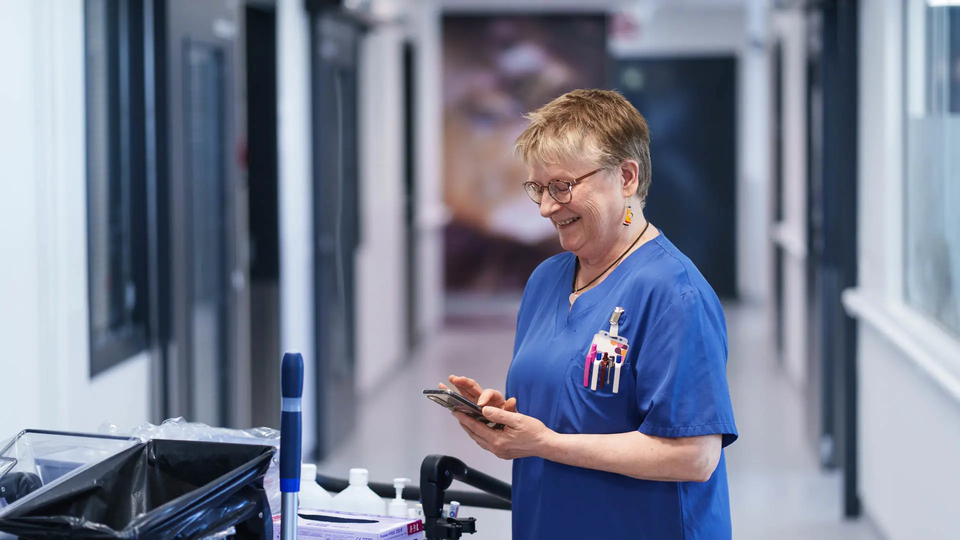 Taina Metsola, domestic assistant at Tampere University Hospital, standing in a hospital corridor wearing work attire.