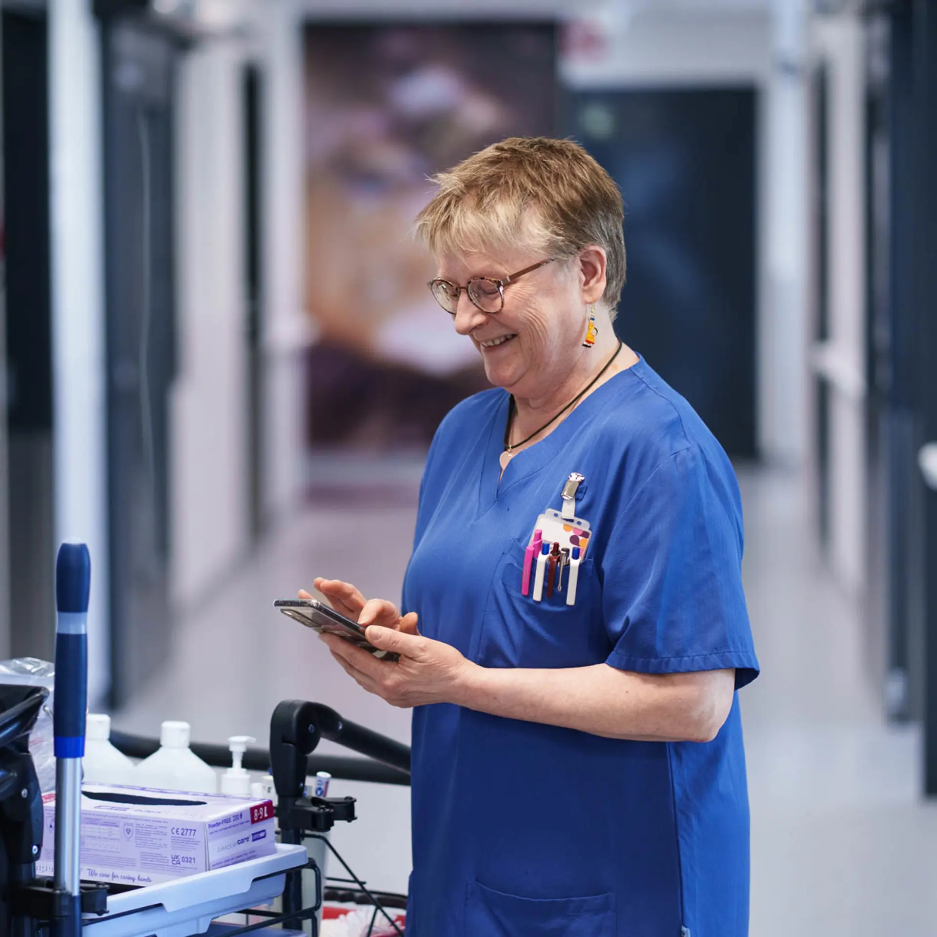 Taina Metsola, domestic assistant at Tampere University Hospital, standing in a hospital corridor wearing work attire.
