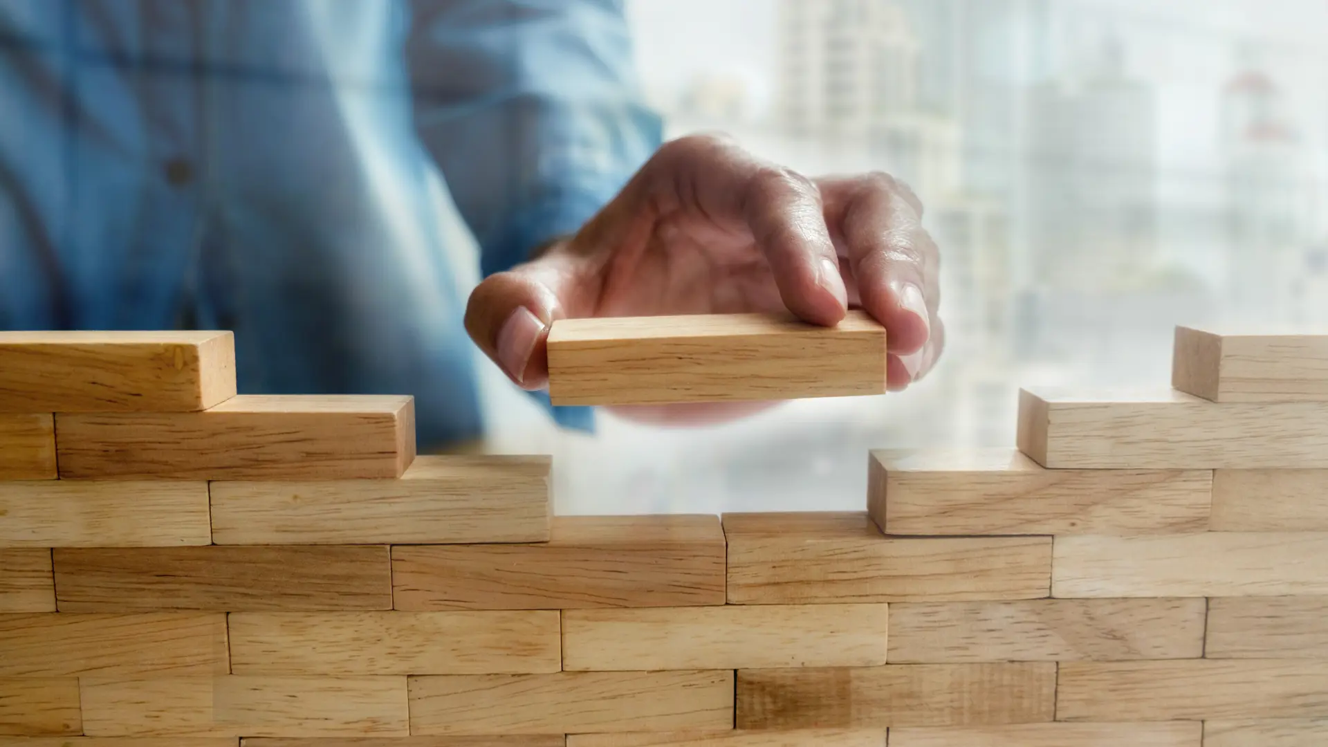 Man stacks wooden pieces on top of each other.