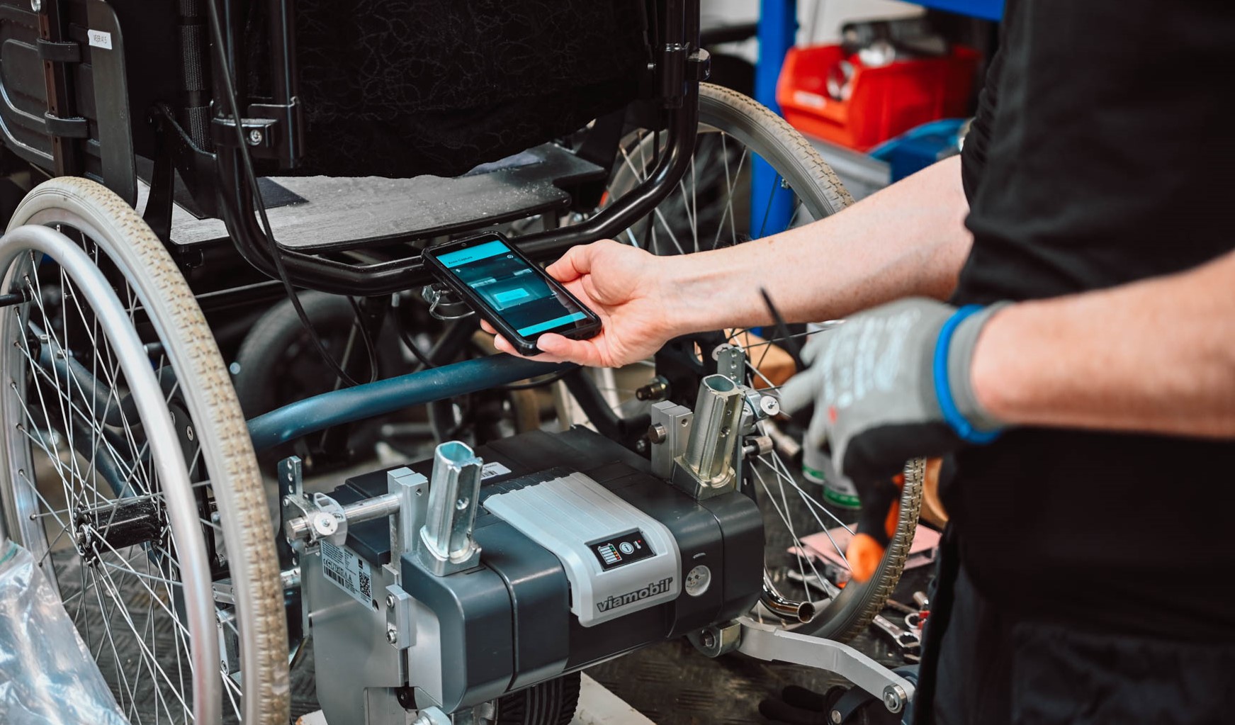 Healthcare staff scanning a barcode on a wheelchair using a mobile device for equipment tracking.