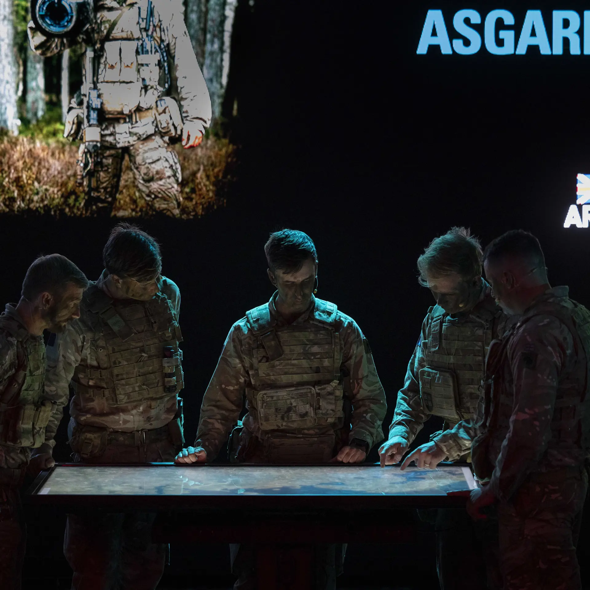 Soldiers stand around a tabletop computer looking at a command-and-control system.