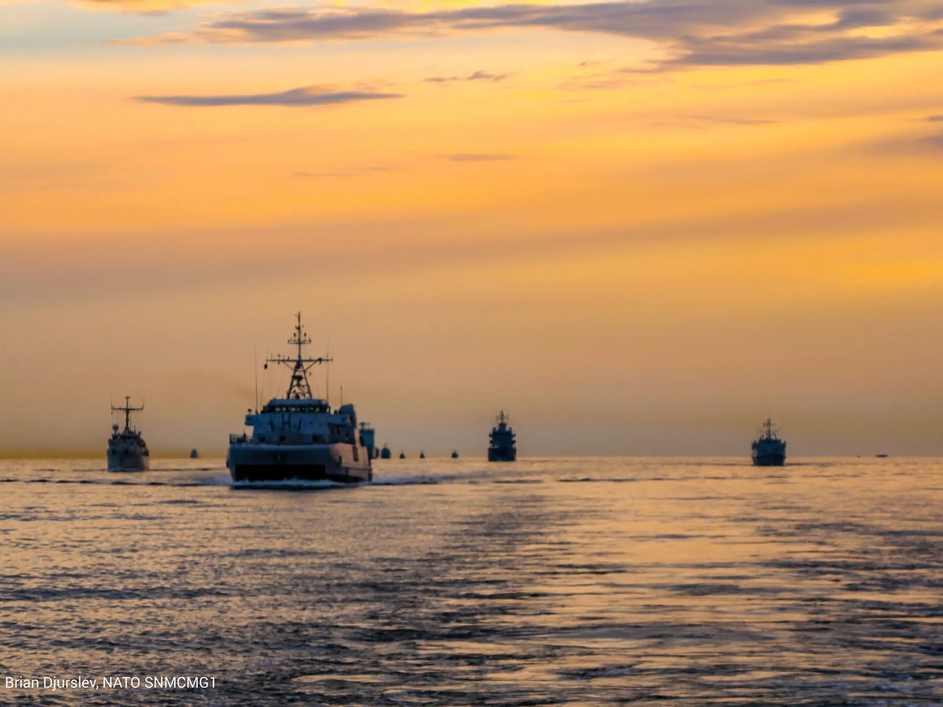 Vessels in formation at sunset performing NATO exercise