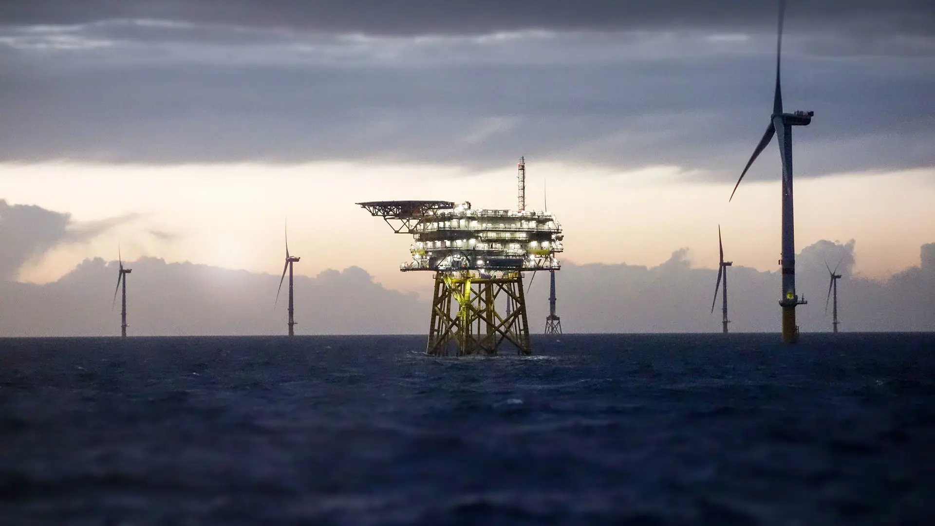 Offshore Substation And Wind Farm In Sunset