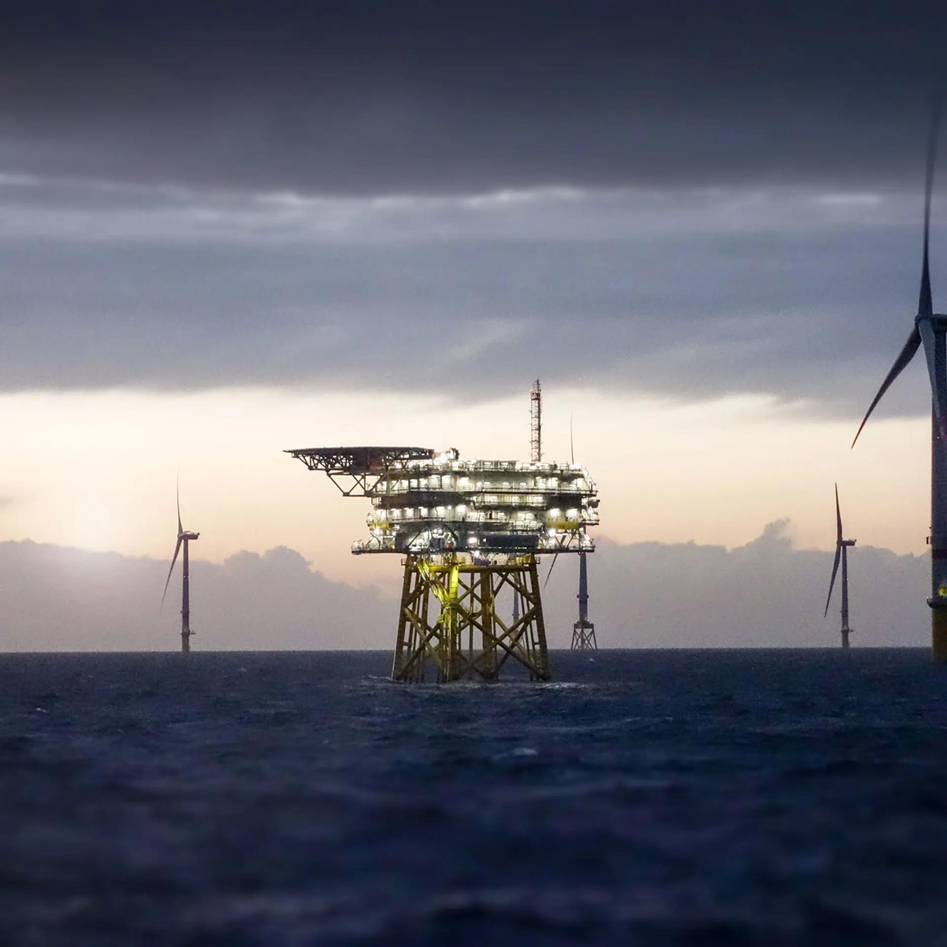 Offshore Substation And Wind Farm In Sunset