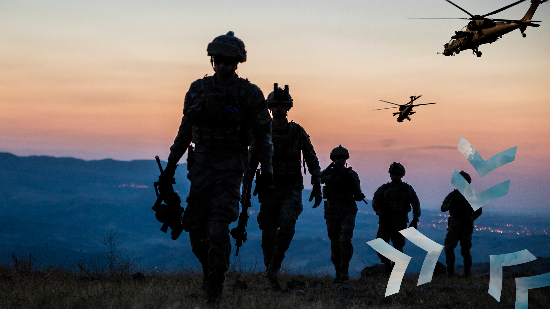 Silhouetted soldiers walk across rugged terrain at sunset with helicopters flying overhead, symbolizing military operations and coordination.