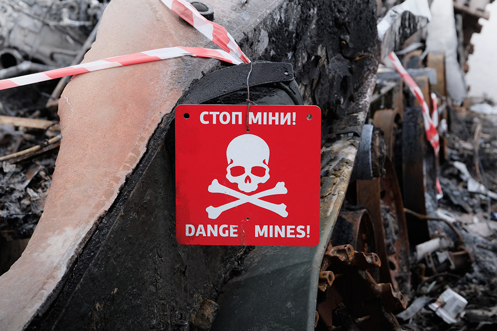 Landmine warning sign featuring a danger symbol warning about explosive hazards nearby.