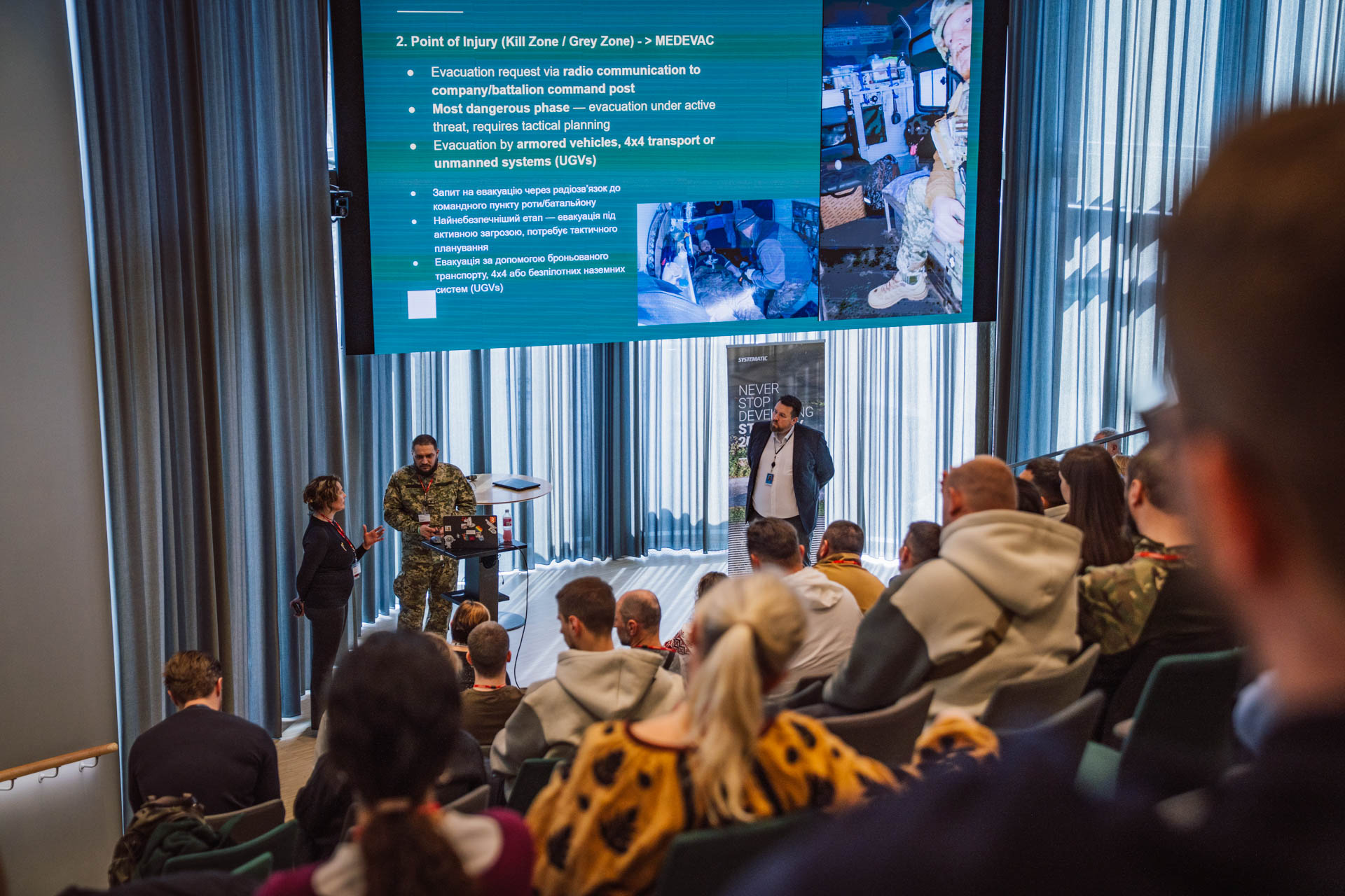 Ukrainian combat medic from the Repower 20 program presenting frontline medical evacuation procedures to a seated audience at Systematic's office in Denmark.