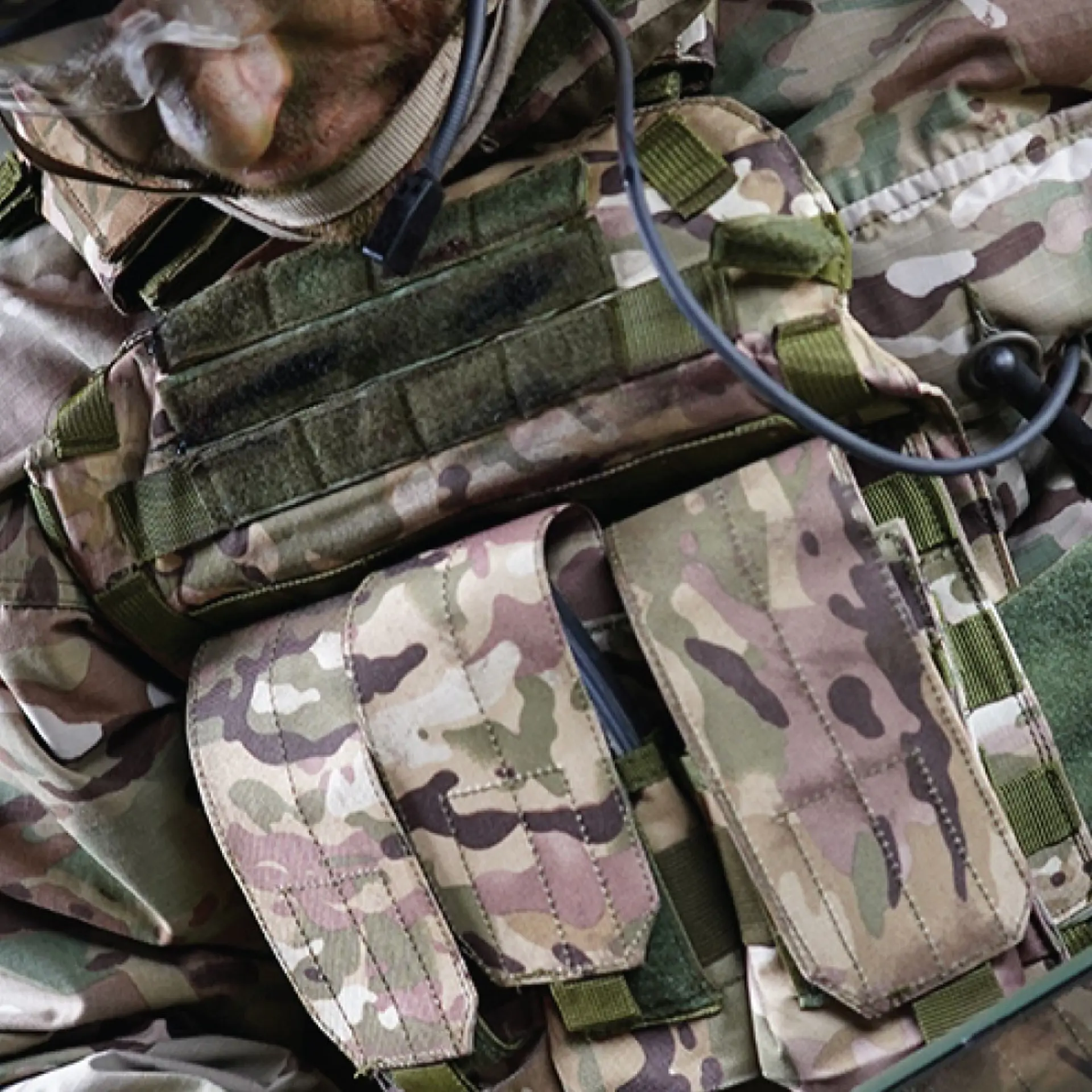 Close-up view of a soldier in camouflage combat gear operating a handheld device with SitaWare Frontline software in a tactical environment.