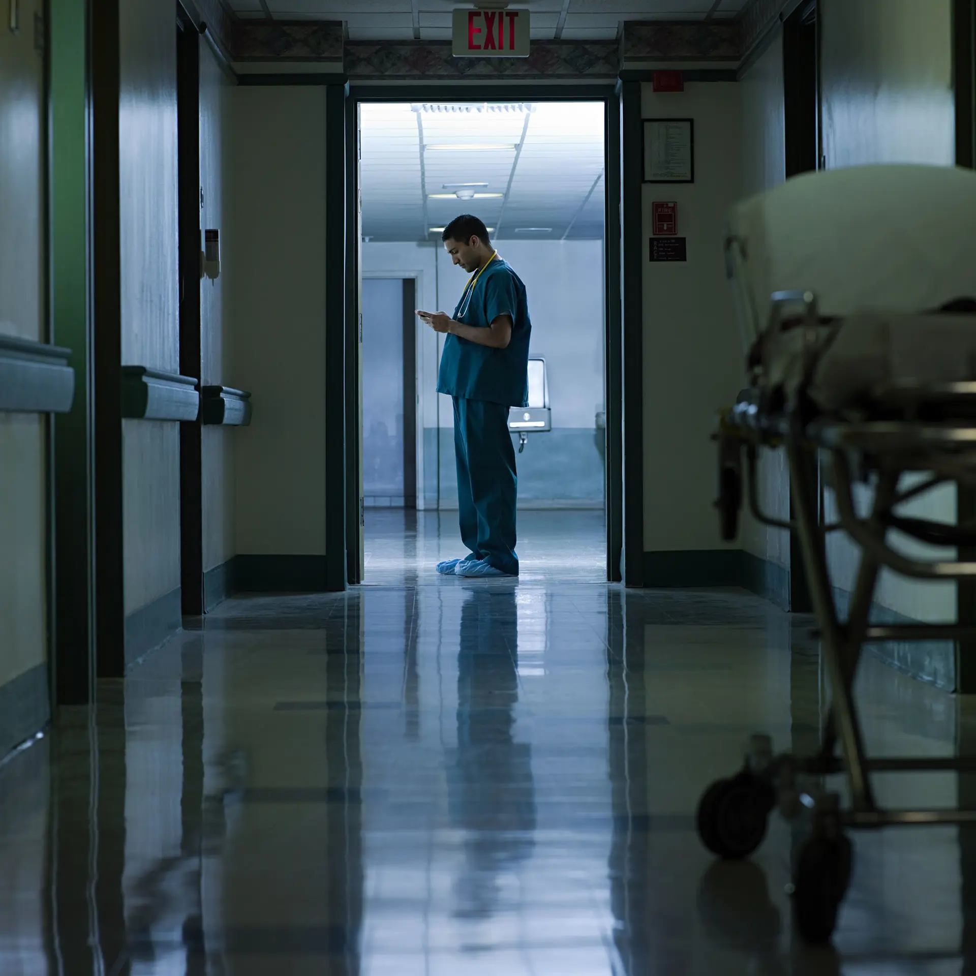 Clinician In Hospital Hallway looking at phone with Columna Flow Clinical Tasking