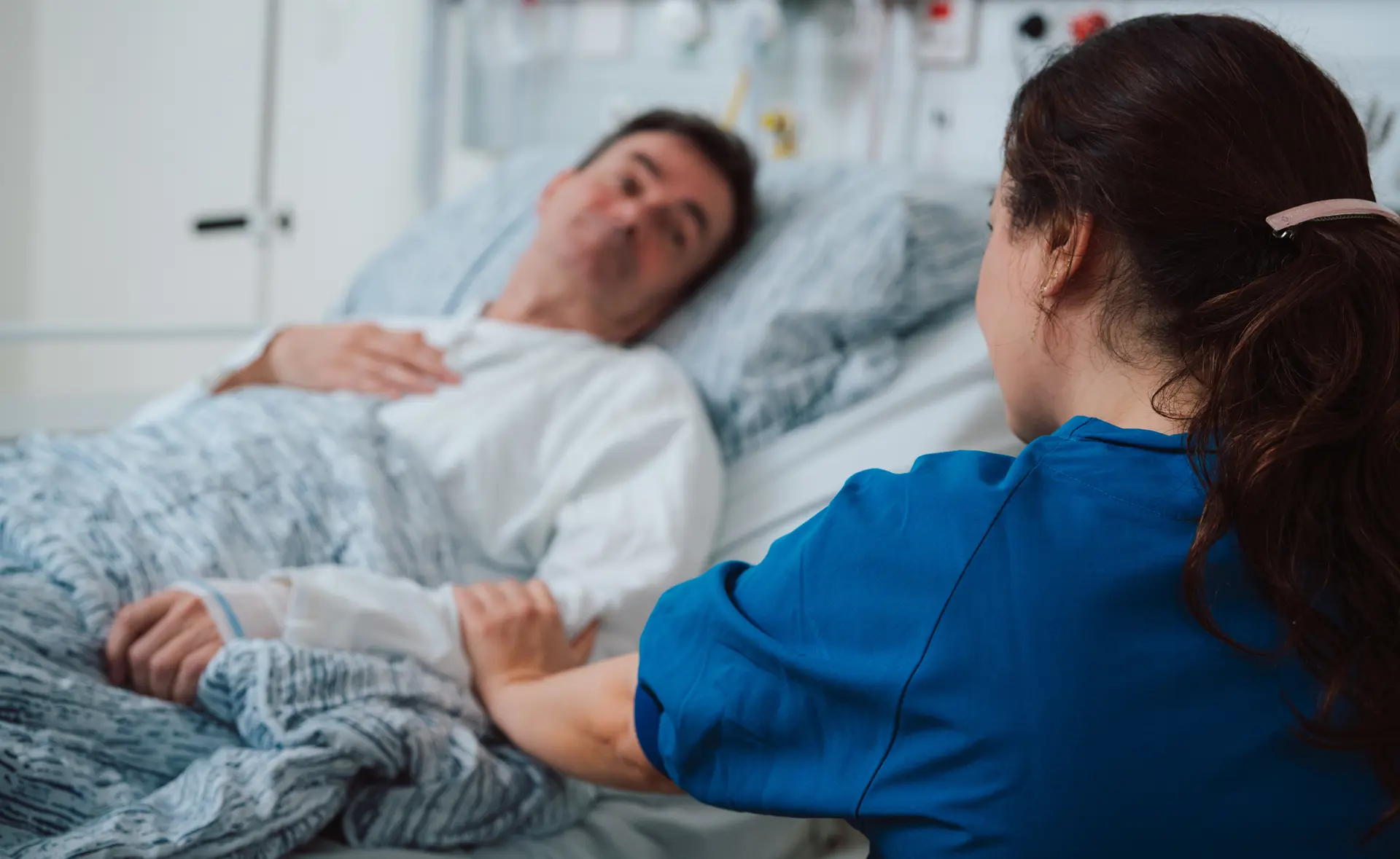 Nurse holding a hand on a bedridden patient