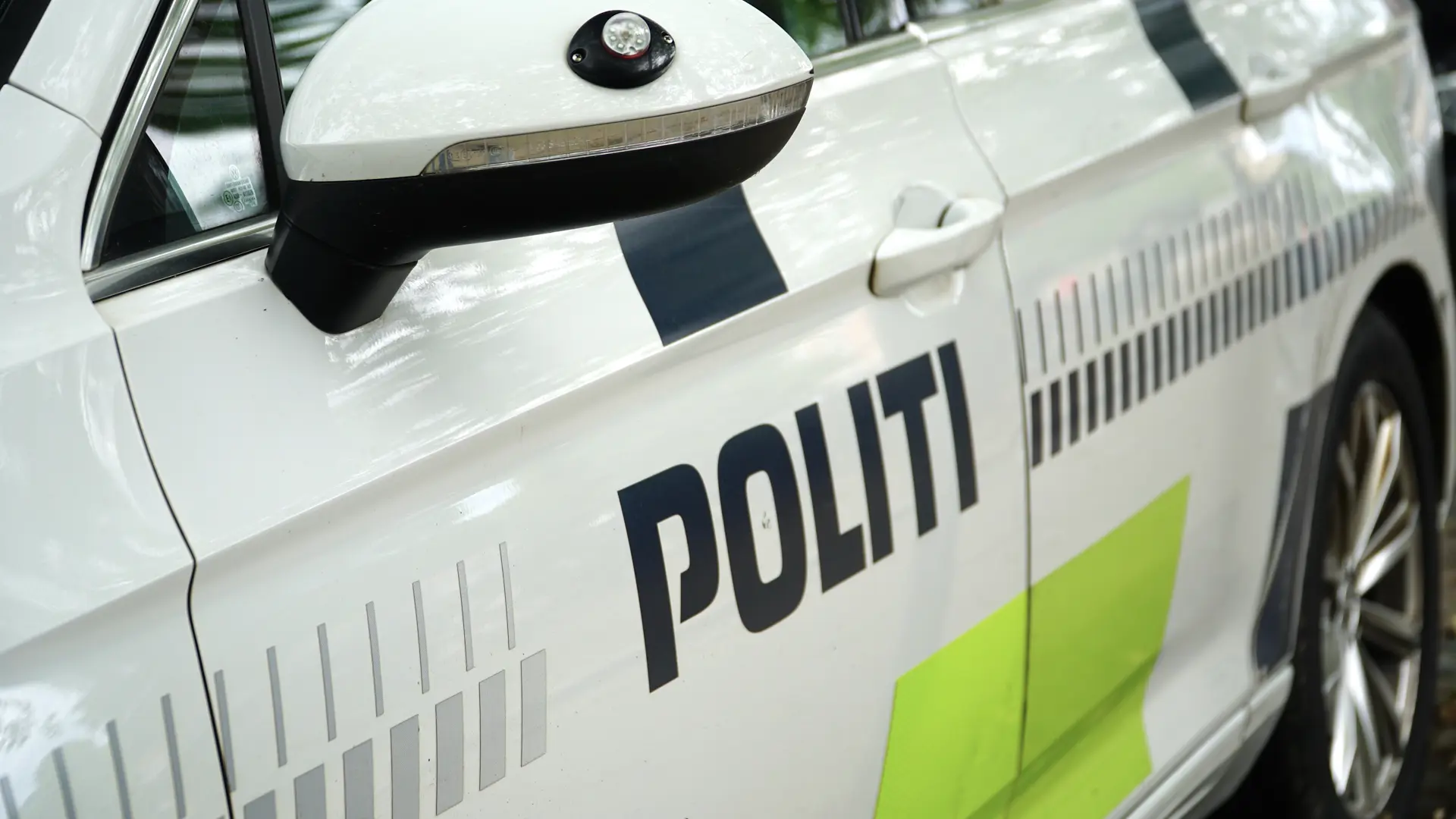 Close-up of a Danish police car with “POLITI” markings, reflective graphics, and side mirror details.