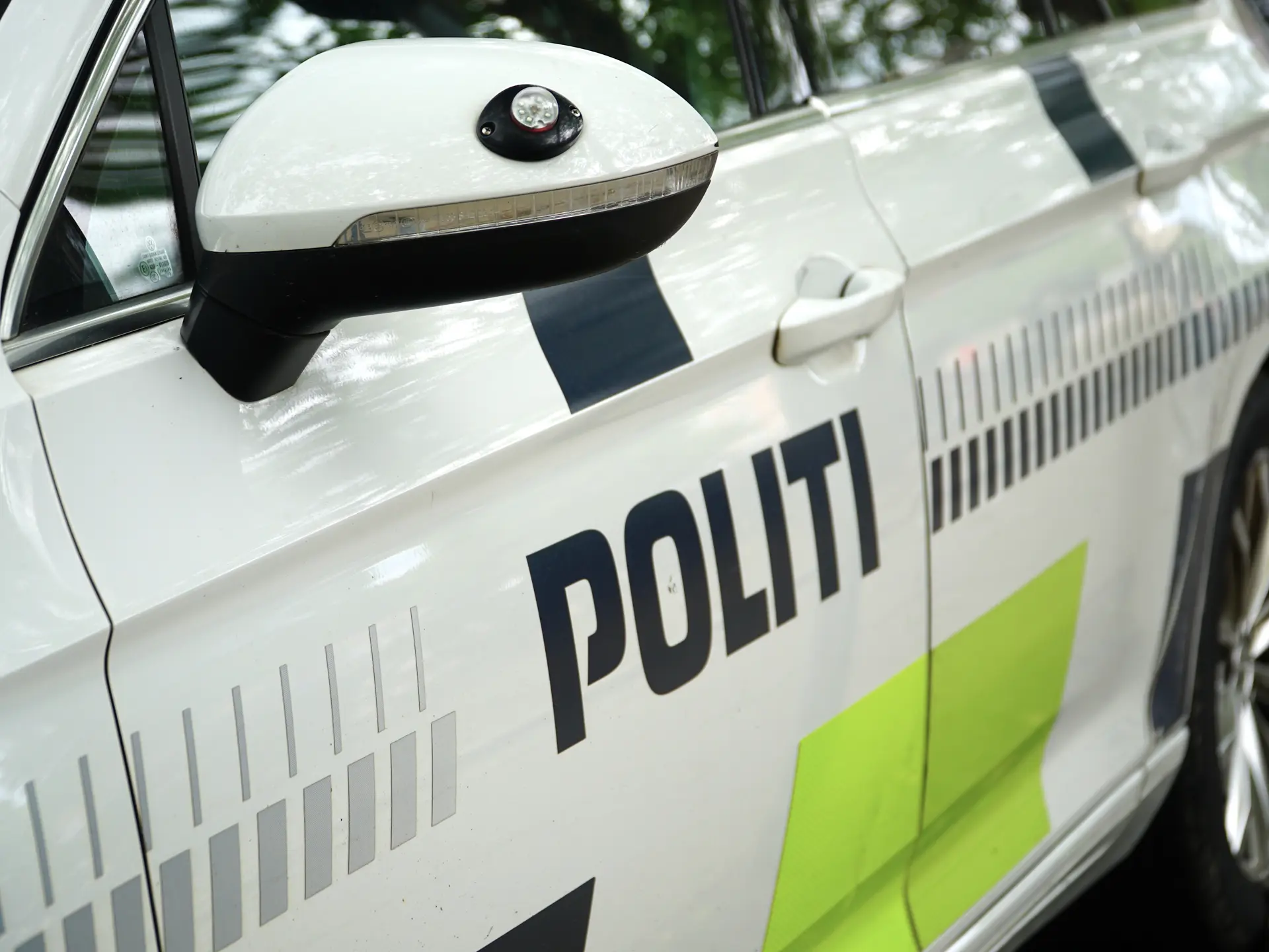 Close-up of a Danish police car with “POLITI” markings, reflective graphics, and side mirror details.