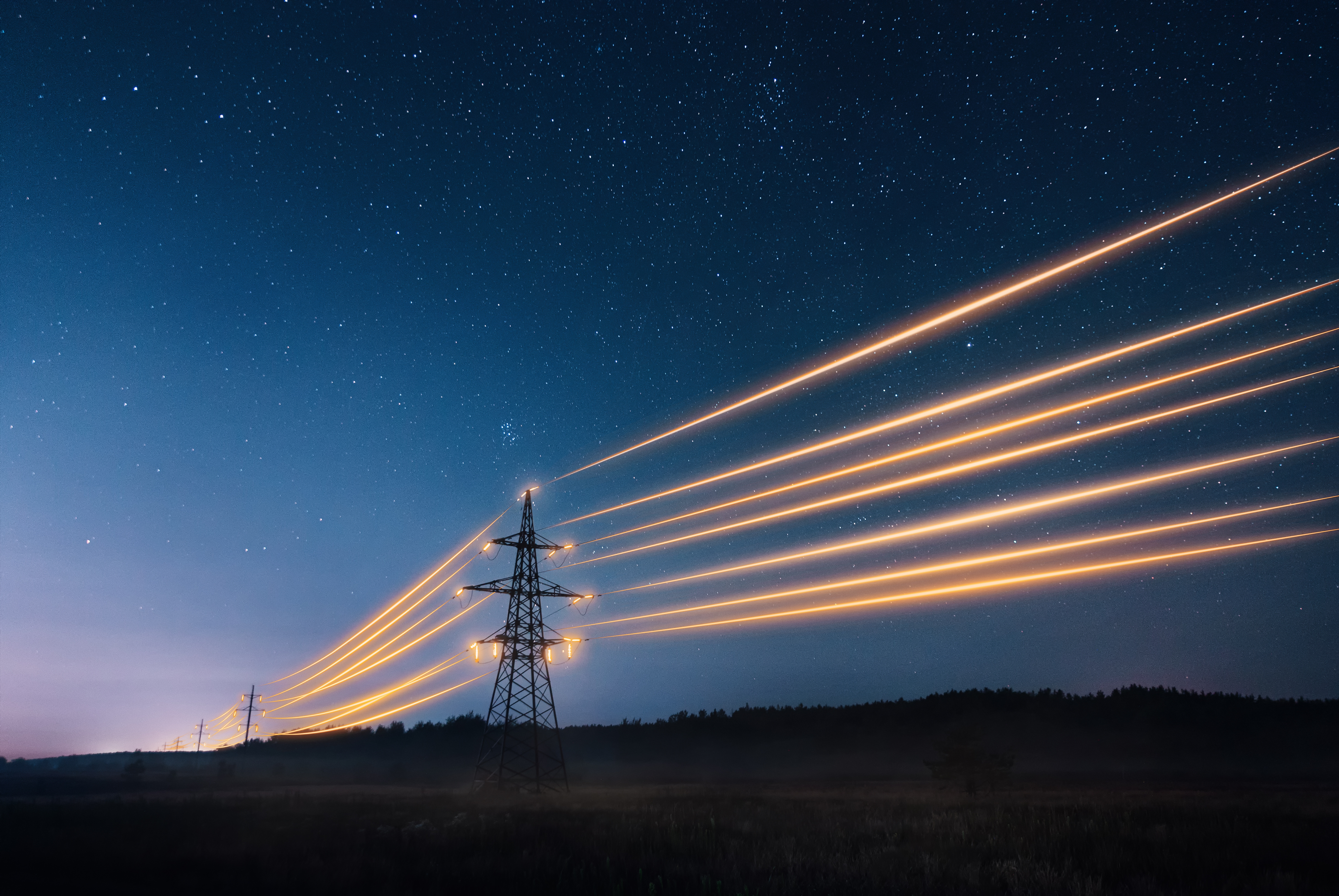 High-voltage power lines glowing with long-exposure light trails stretching across a night sky filled with stars.