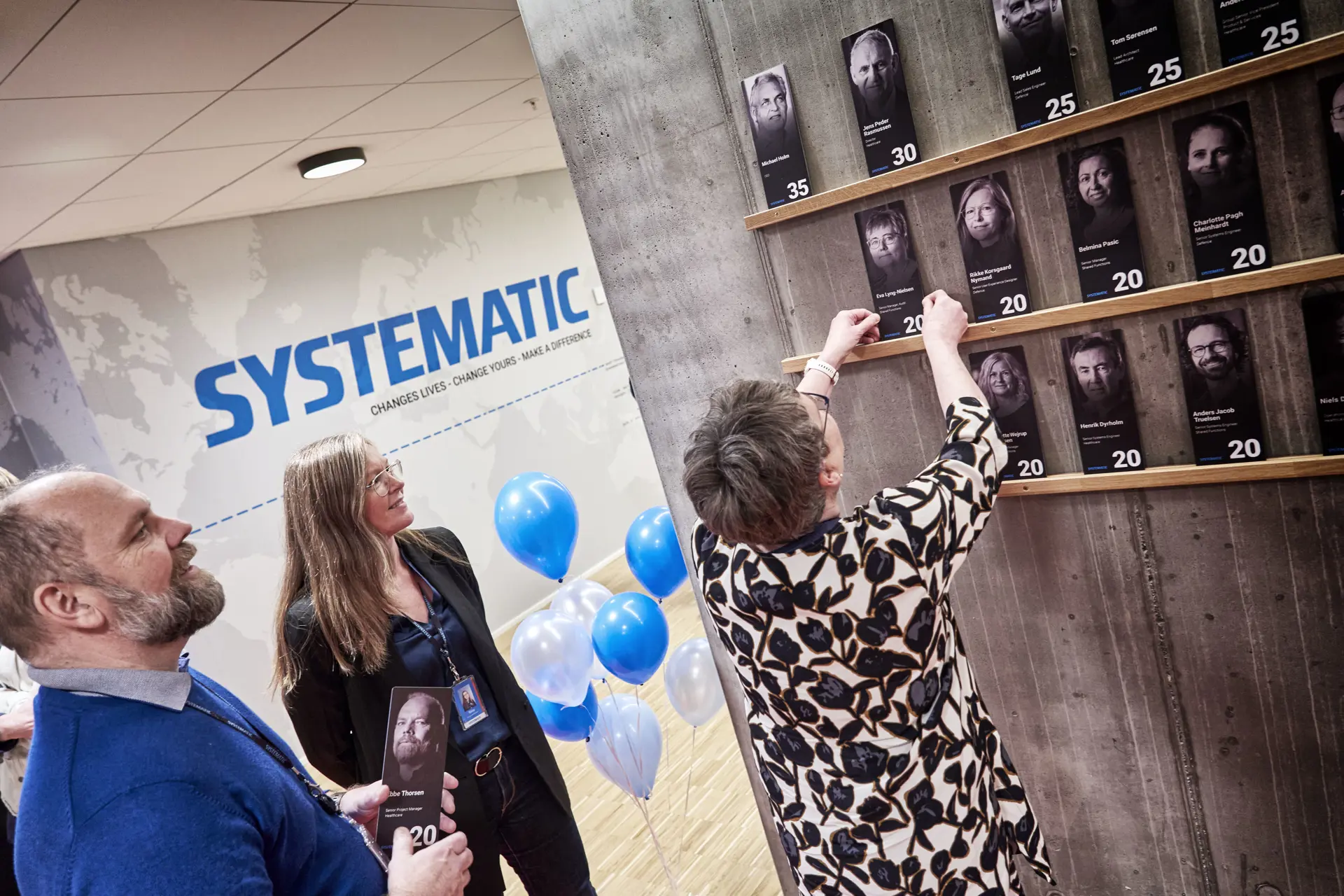 An employee puts her picture up on the Systematic wall of fame